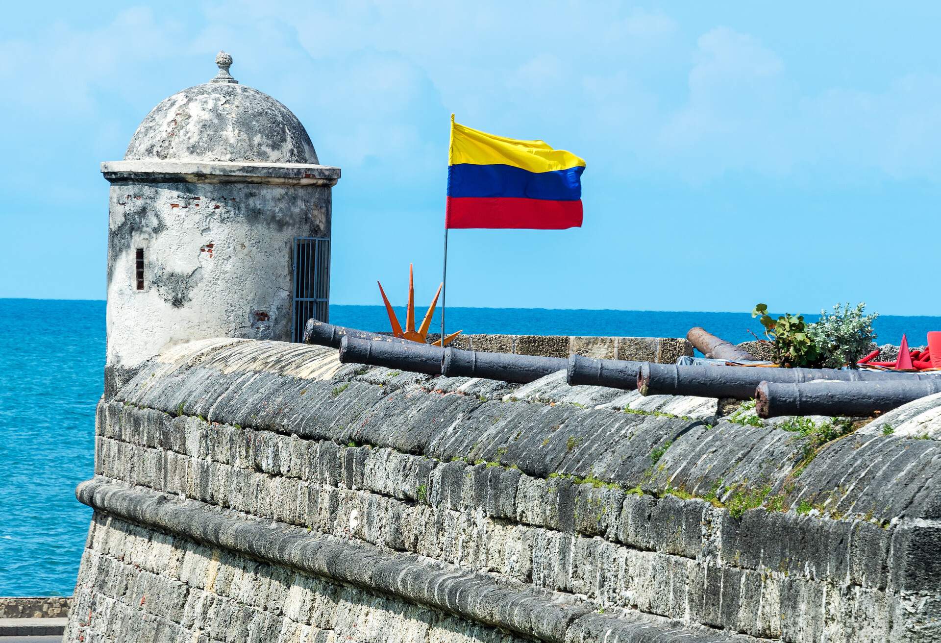 Defensive wall of Cartagena with a Colombian flag waving and several cannons visible in the old town of Cartagena, Colombia