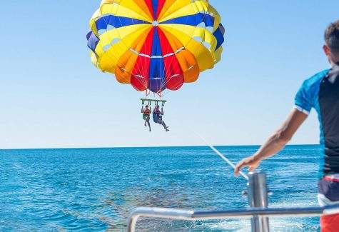 Happy couple Parasailing in Dominicana beach in summer. Couple under parachute hanging mid air. Having fun. Tropical Paradise. Positive human emotions, feelings, joy.