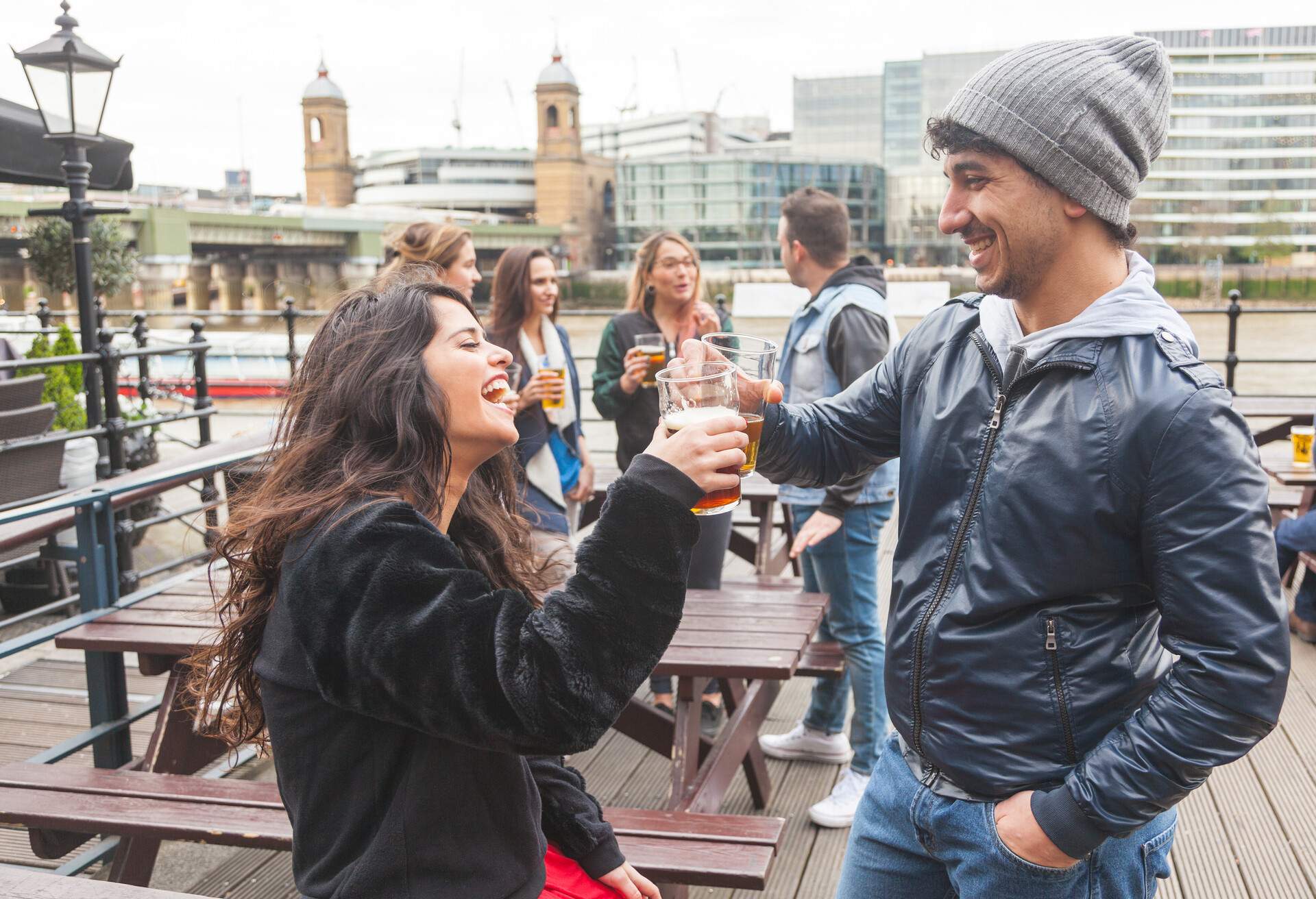 Young couple enjoying a beer at pub in London with more people on background. Outdoor scene, winter season, love and friendship concepts.; Shutterstock ID 282996266; Purpose: Content; Brand (KAYAK, Momondo, Any): Any