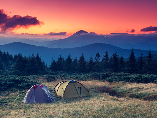 acampamento de barracas em frente a uma cadeia de montanhas