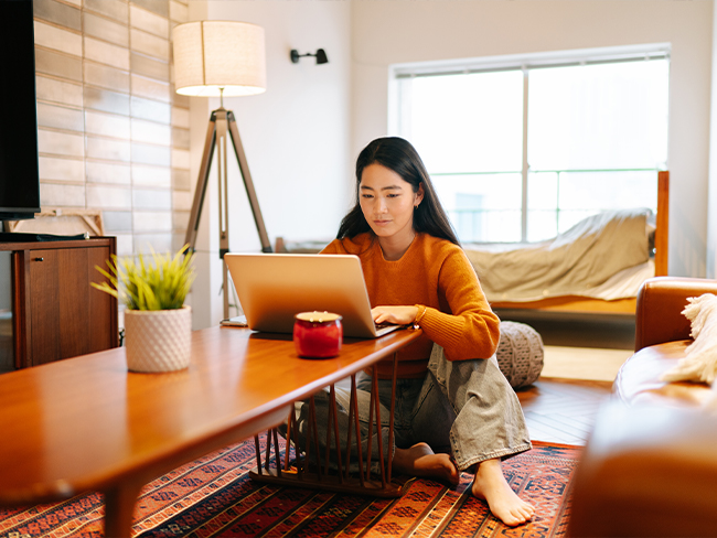 mulher usando um laptop sentada no chão no meio da casa