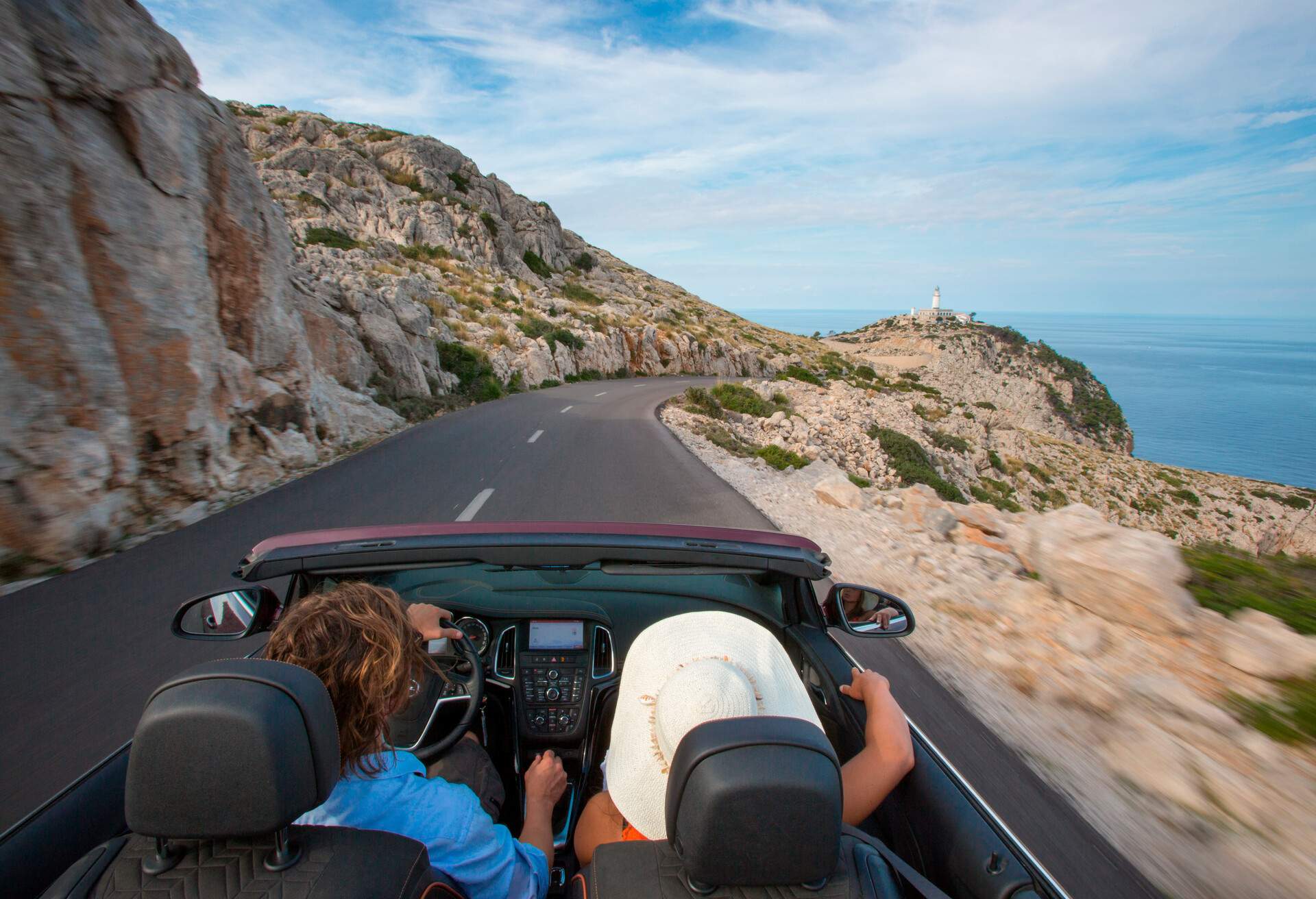Two people in a car, driving on a road in Spain