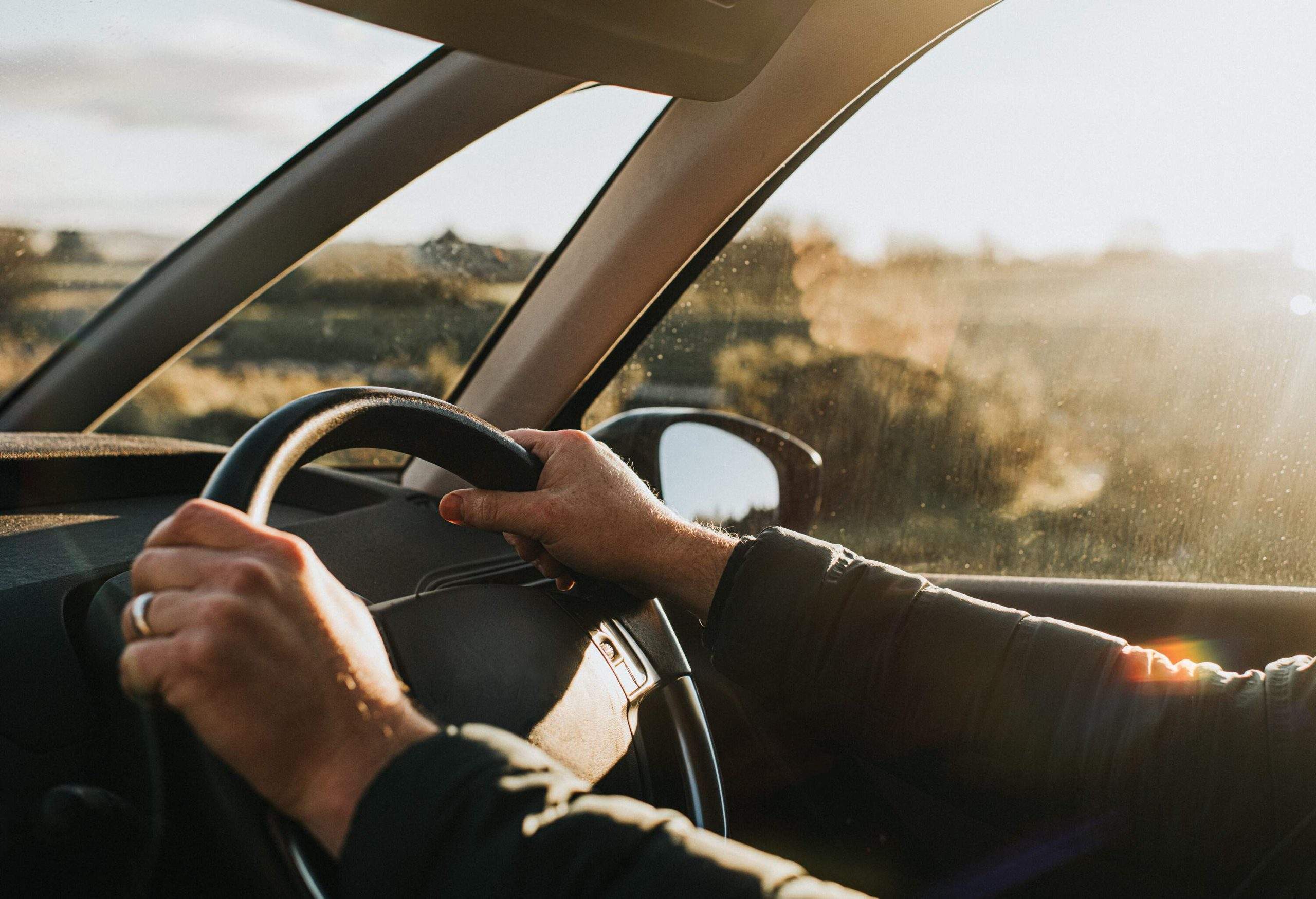 Hands holding a car's steering wheel.