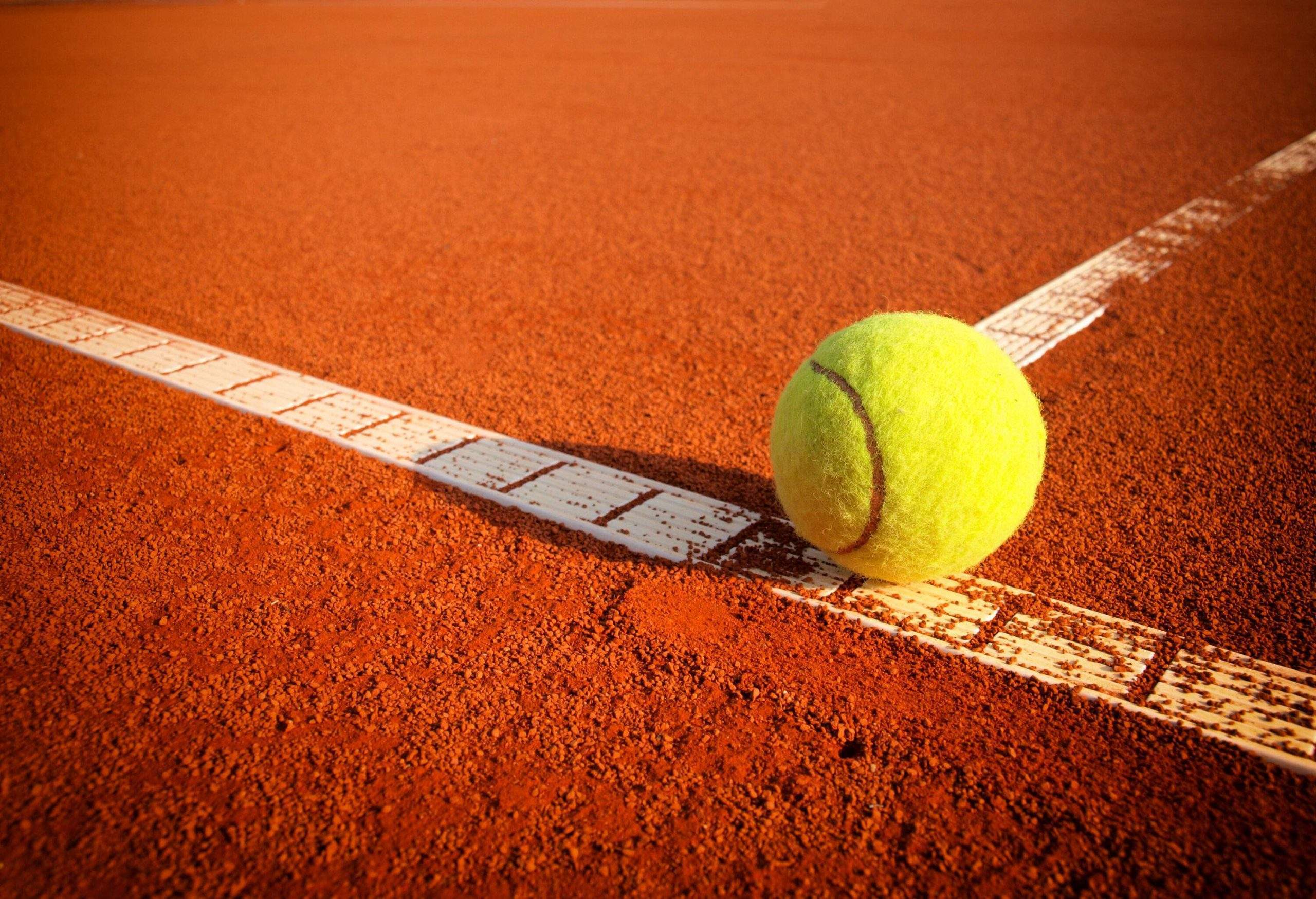 A tennis ball on a tennis clay court.