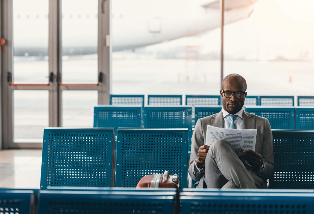 A businessman reading a paper while sitting in one of the terminal's row seats.