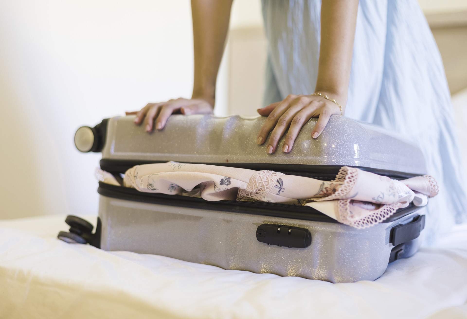 A woman closing a suitcase before starting a road trip