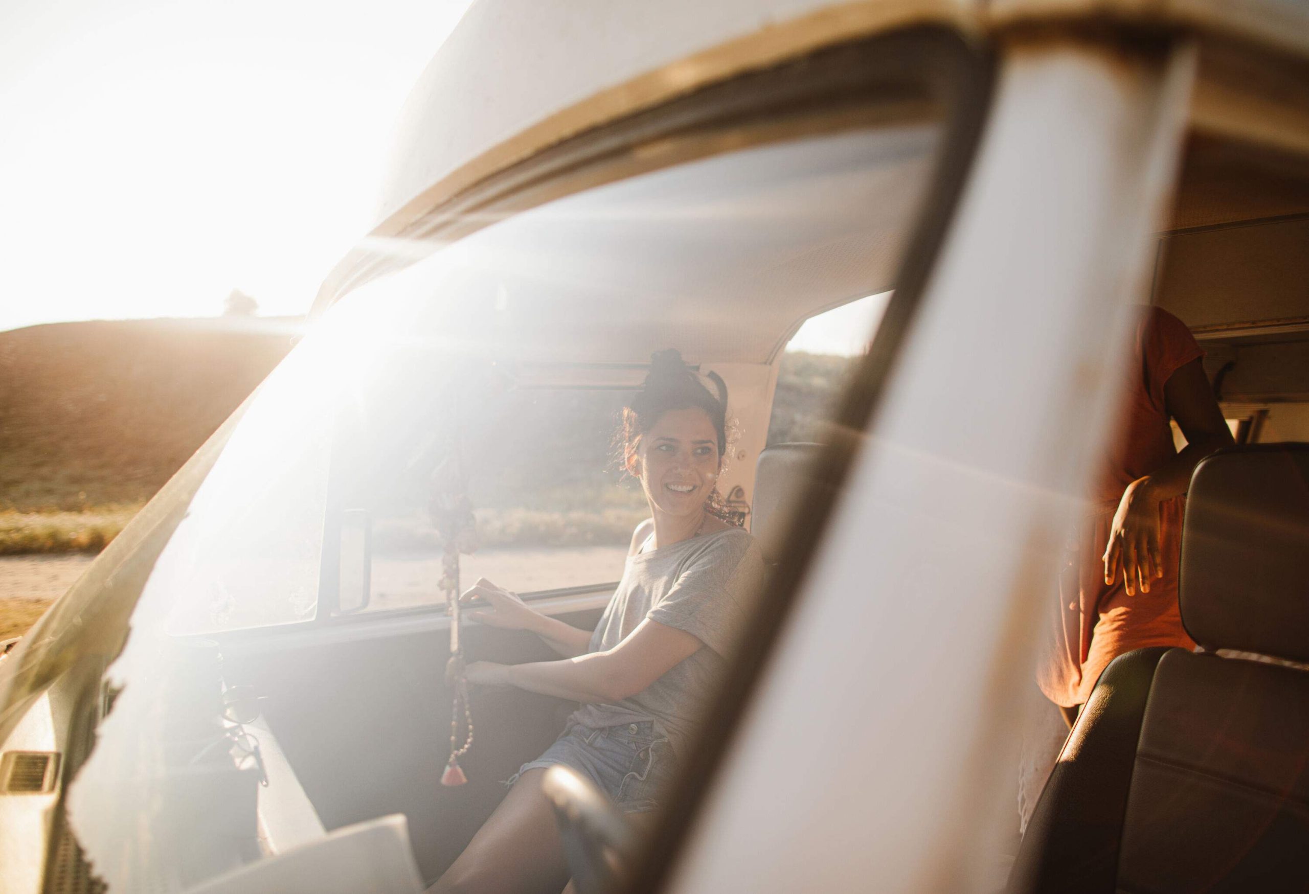 A female passenger exits a van viewed from the car's windshield.