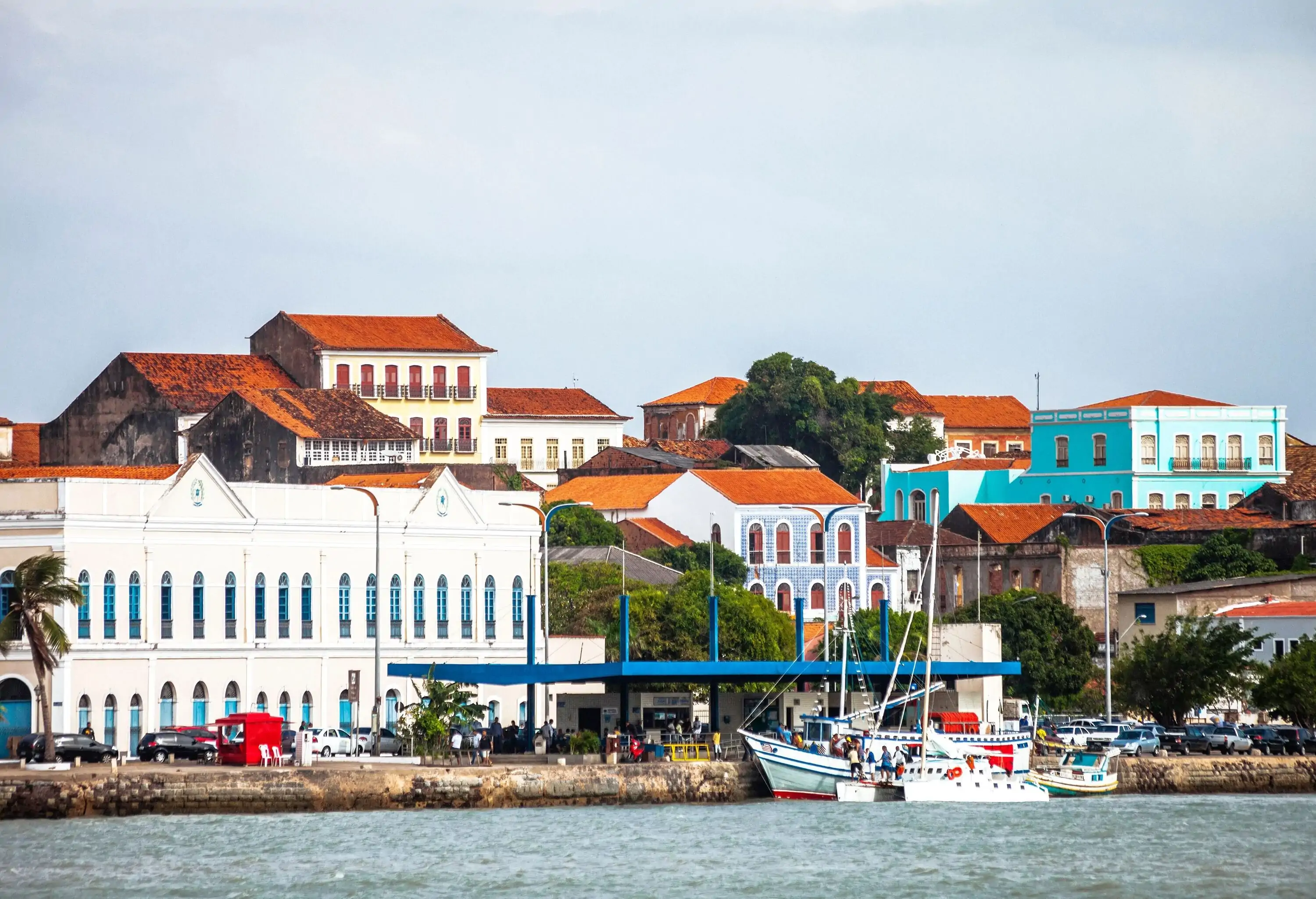 Colourful colonial buildings cover the hill alongside a bustling promenade lining the seashore.