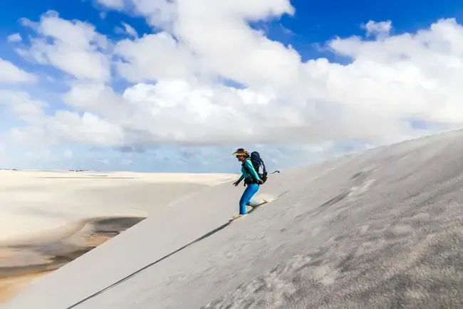 Mulher descendo as dunas no Parque Nacional dos Lençóis Maranhenses