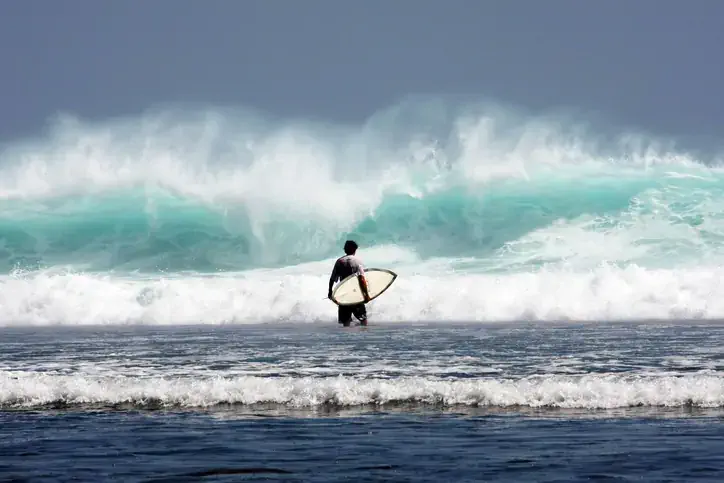 Surfista entrando no mar de Bali