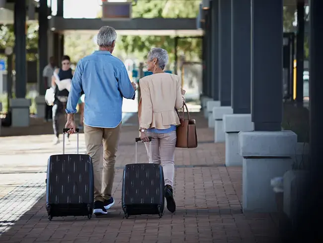 foto de idosos de costas caminhando levando suas malas