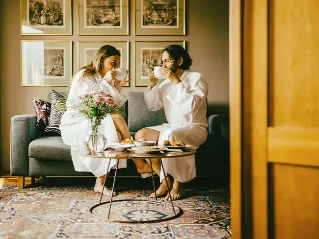 foto de um casal tomando café da manhã em um sofá de hotel