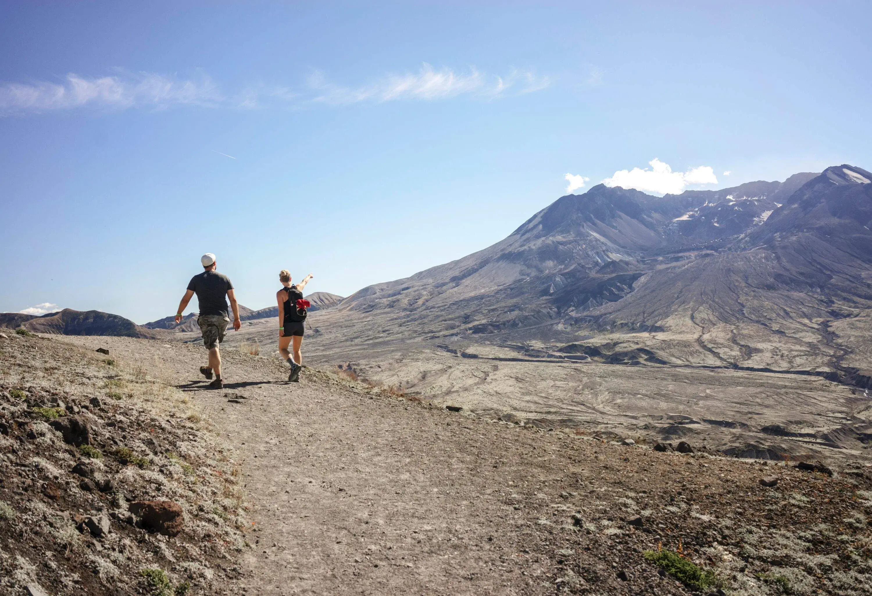 Two people hiking up a crater mountain on a sunny summer day