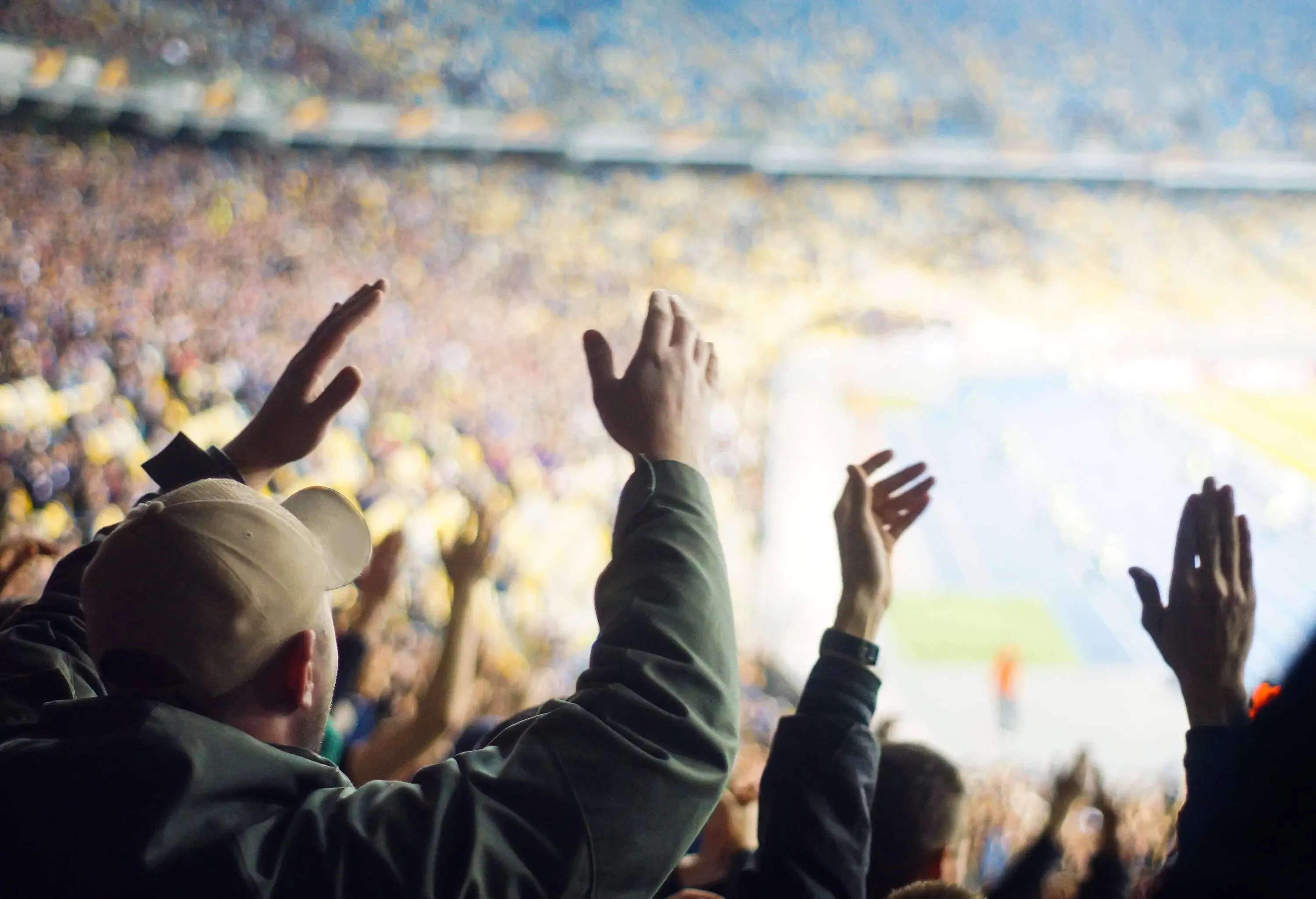 A large crowd cheering wildly during a ballgame.