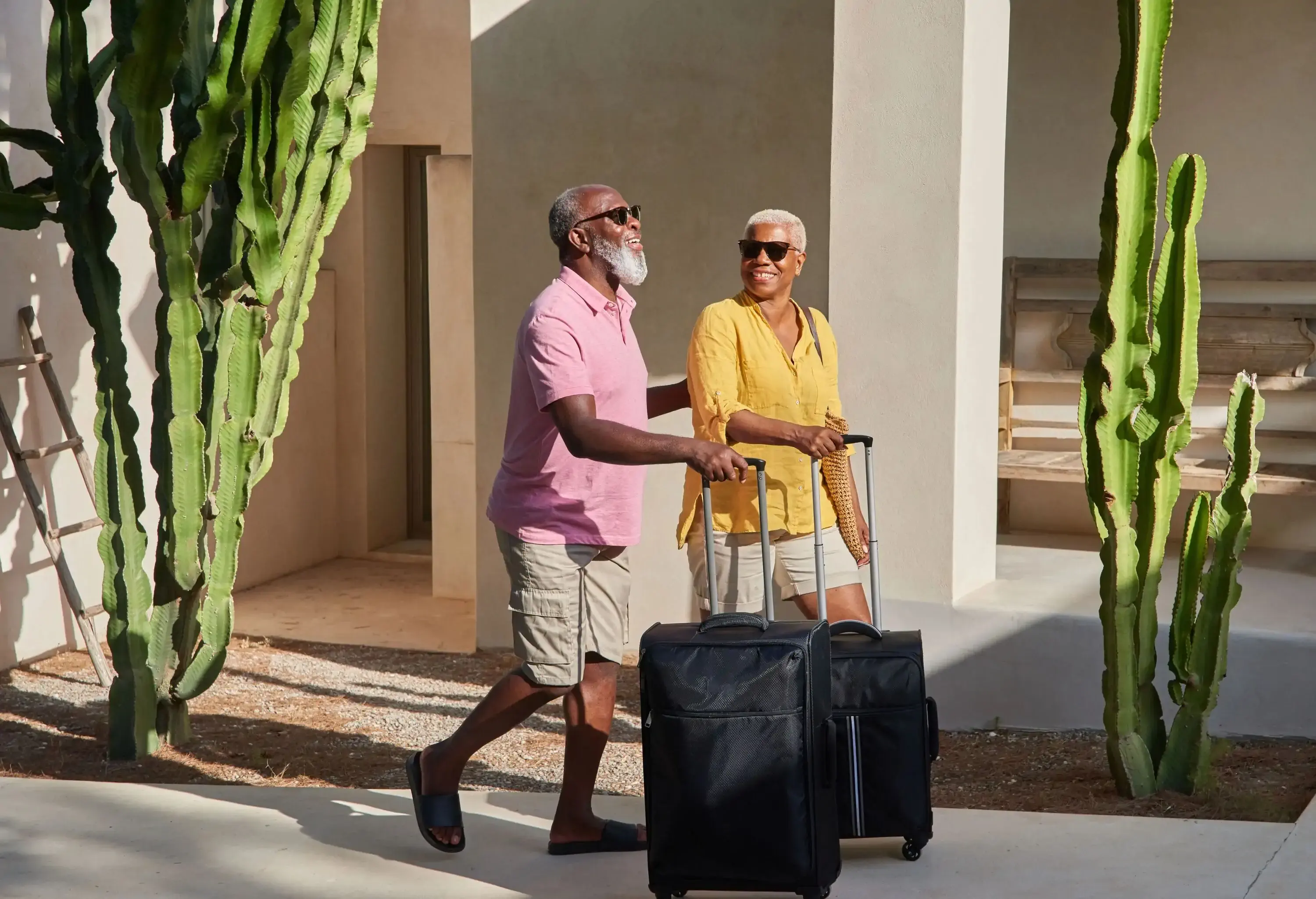 A mature couple walk luggage up the entrance of a luxury villa