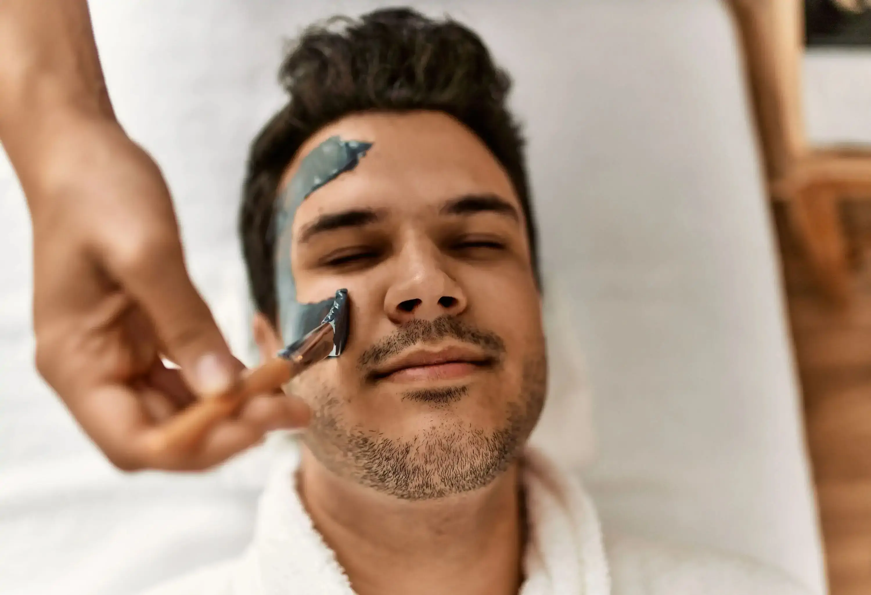 Man reciving facial treatment at beauty center.