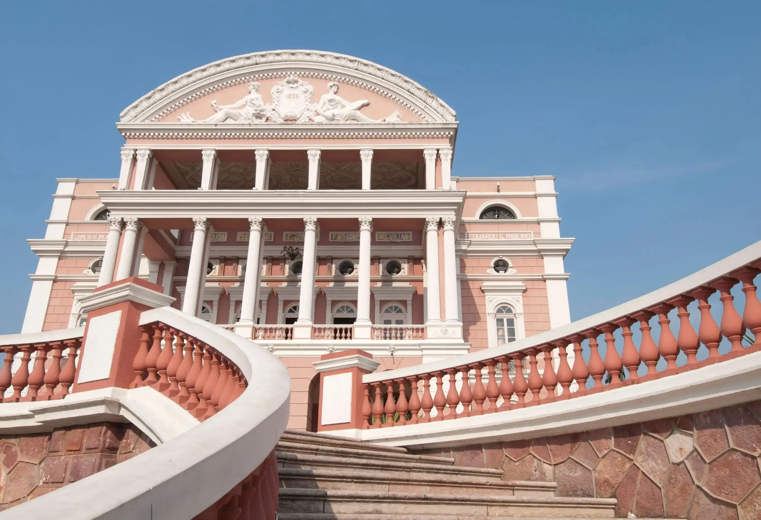 A staircase leading up to the Amazon Theatre in Manaus, Brazil, which is set against a blue sky.