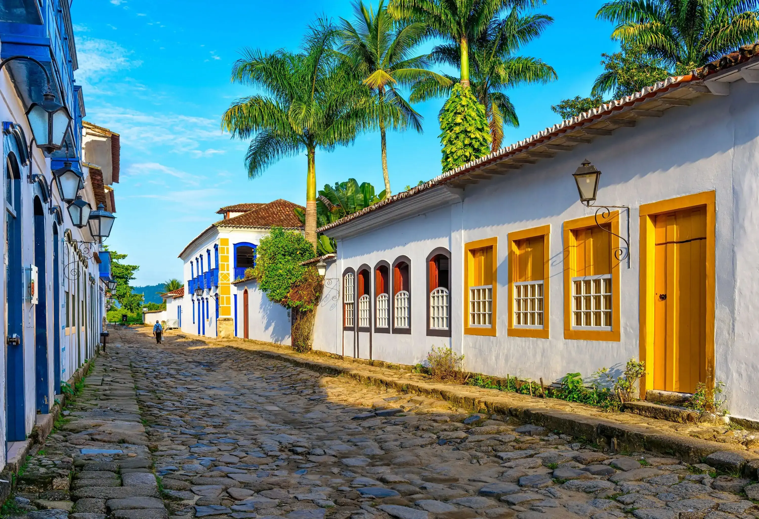 A lone man walking through the cobbled street between the colourful traditional houses.