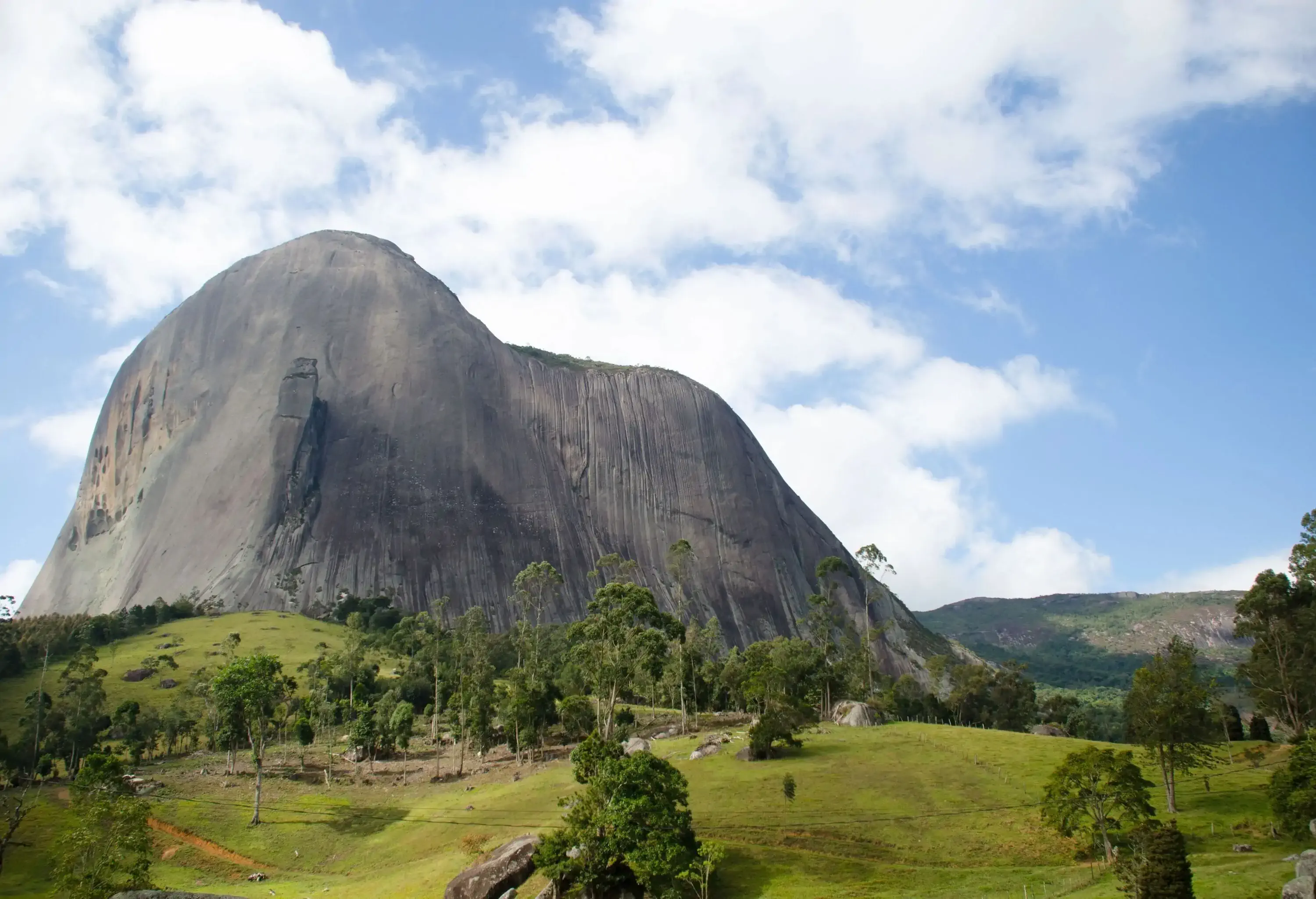 A smooth-surfaced rock formation looming over the soft hills in the valley.
