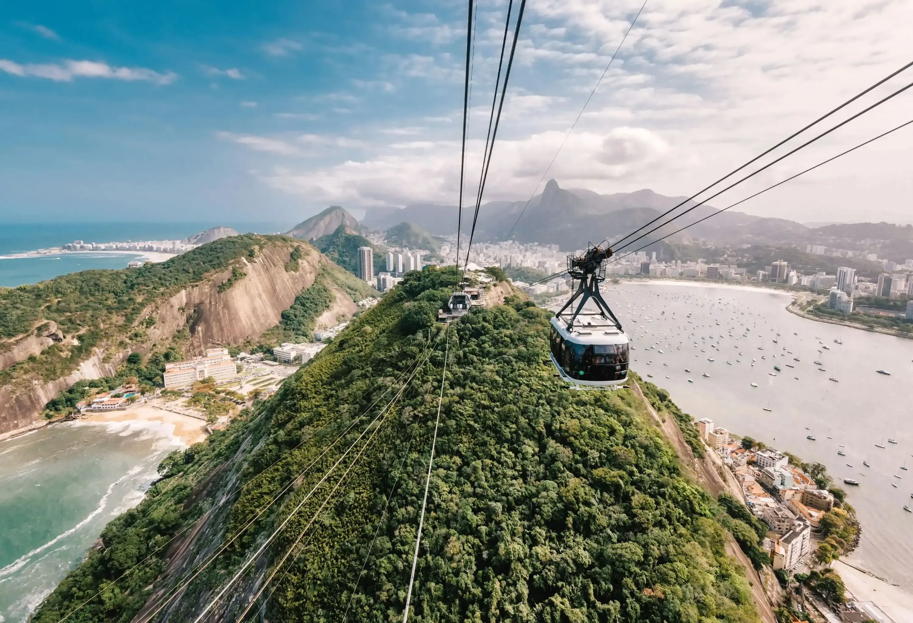 view from sugar loaf on Rio cityscape with mountain range and Botafogo Bay and cable car coming up