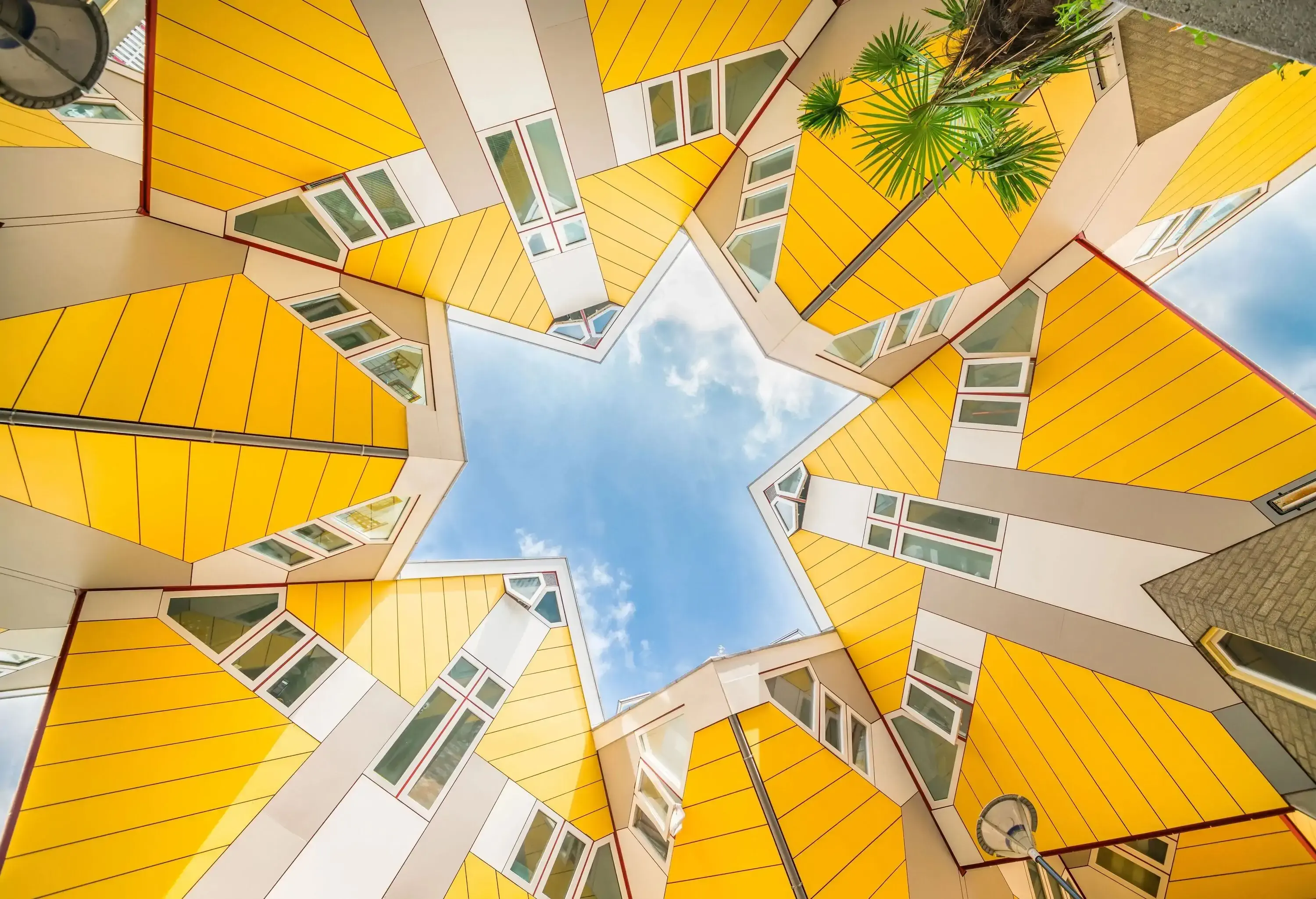 A group of futuristic and iconic yellow innovative houses resembling a cluster of cubes standing on their corners, seen from below.