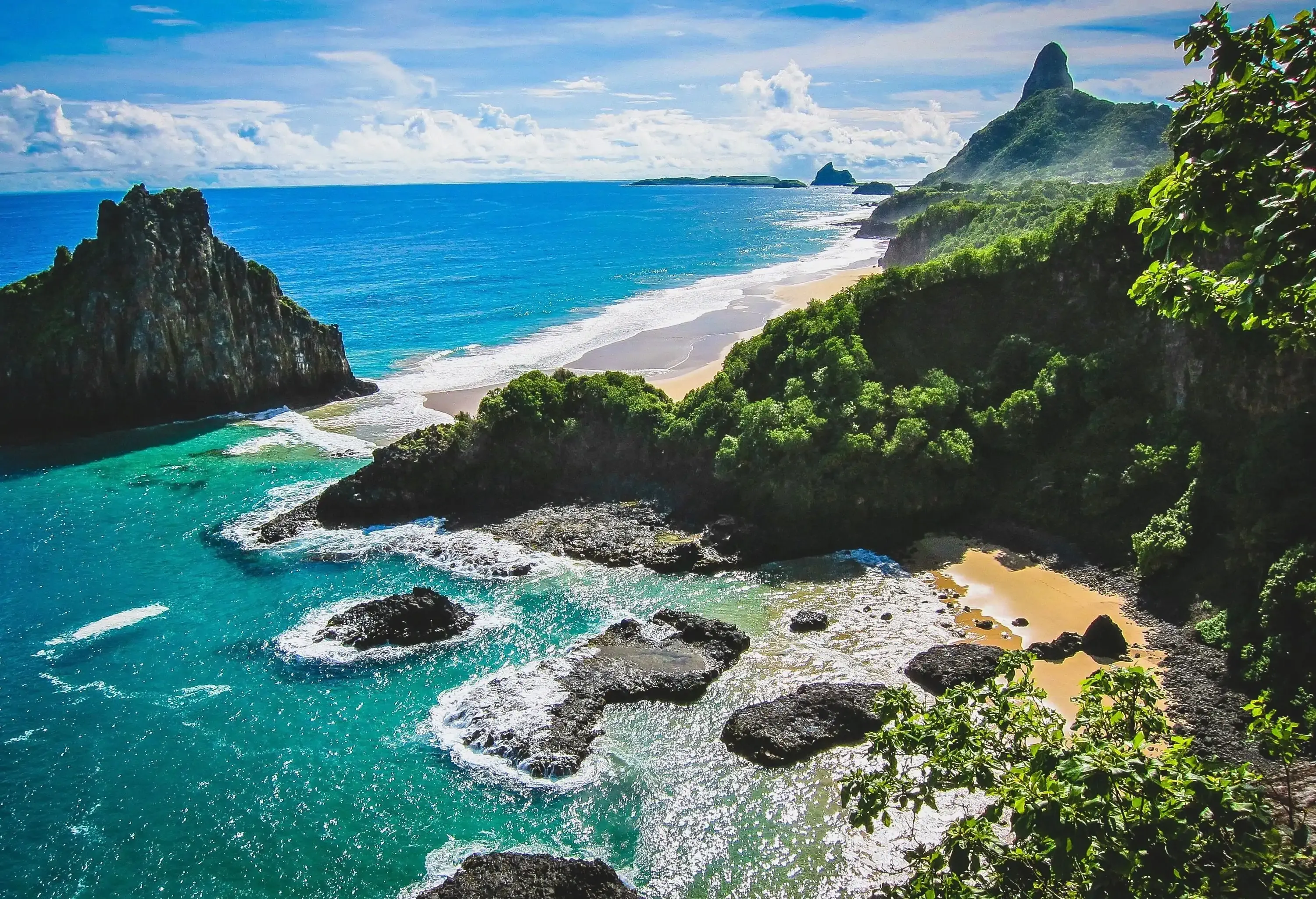 A crystal-clear bay sheltered by a cliff and littered with rocks across the water.
