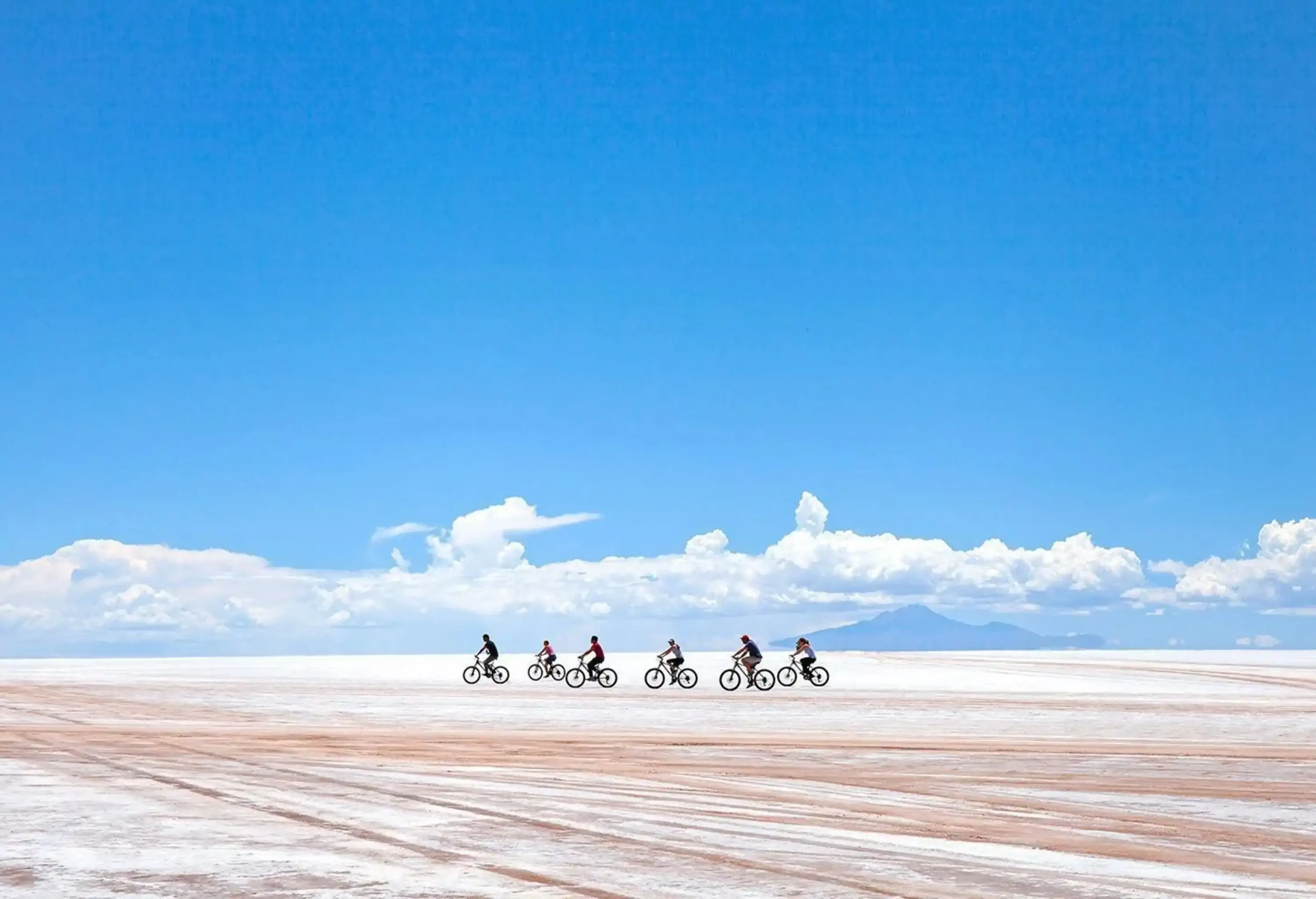 A group of cyclists riding through the vast desert of salt.