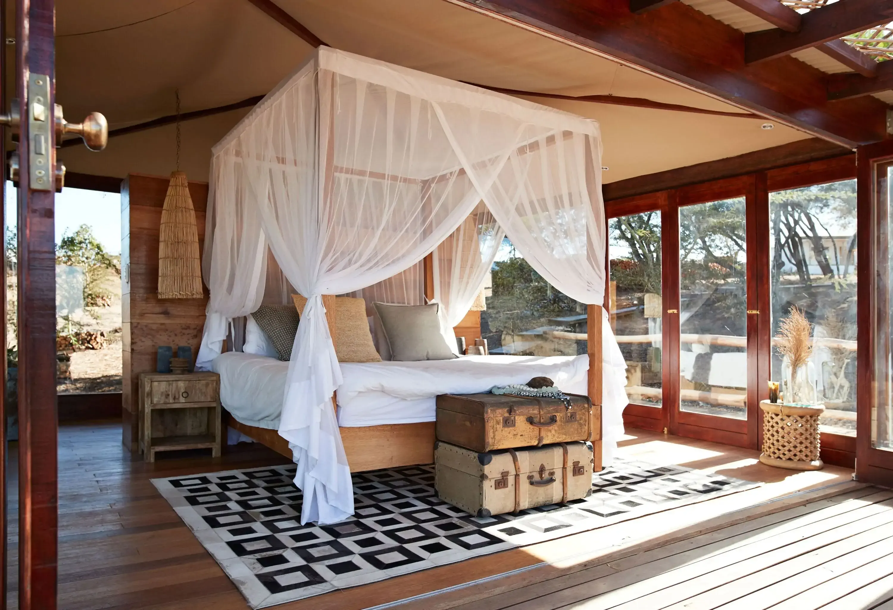 A soothing bedroom cabin with natural sunlight coming in through the glass doors.
