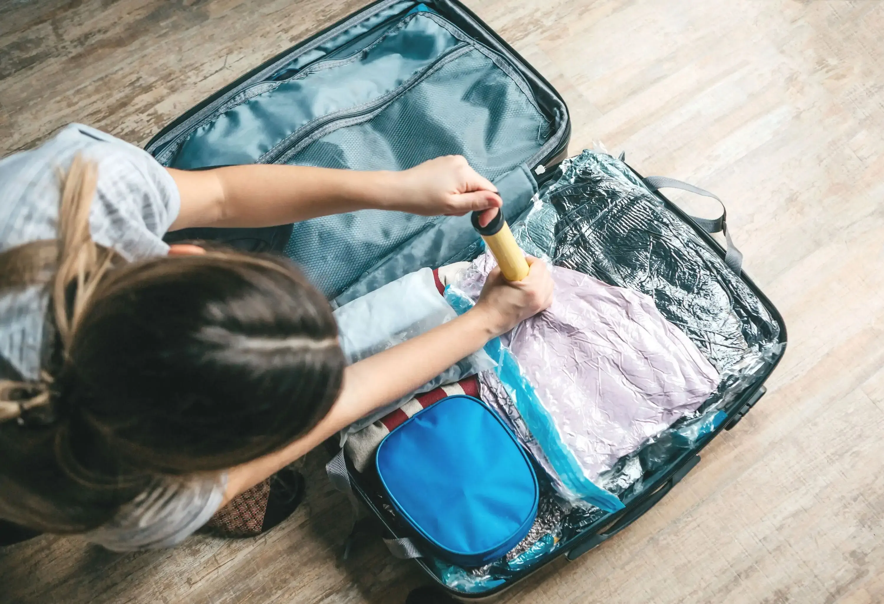 A woman packing her hand luggage and zipping the suitecase