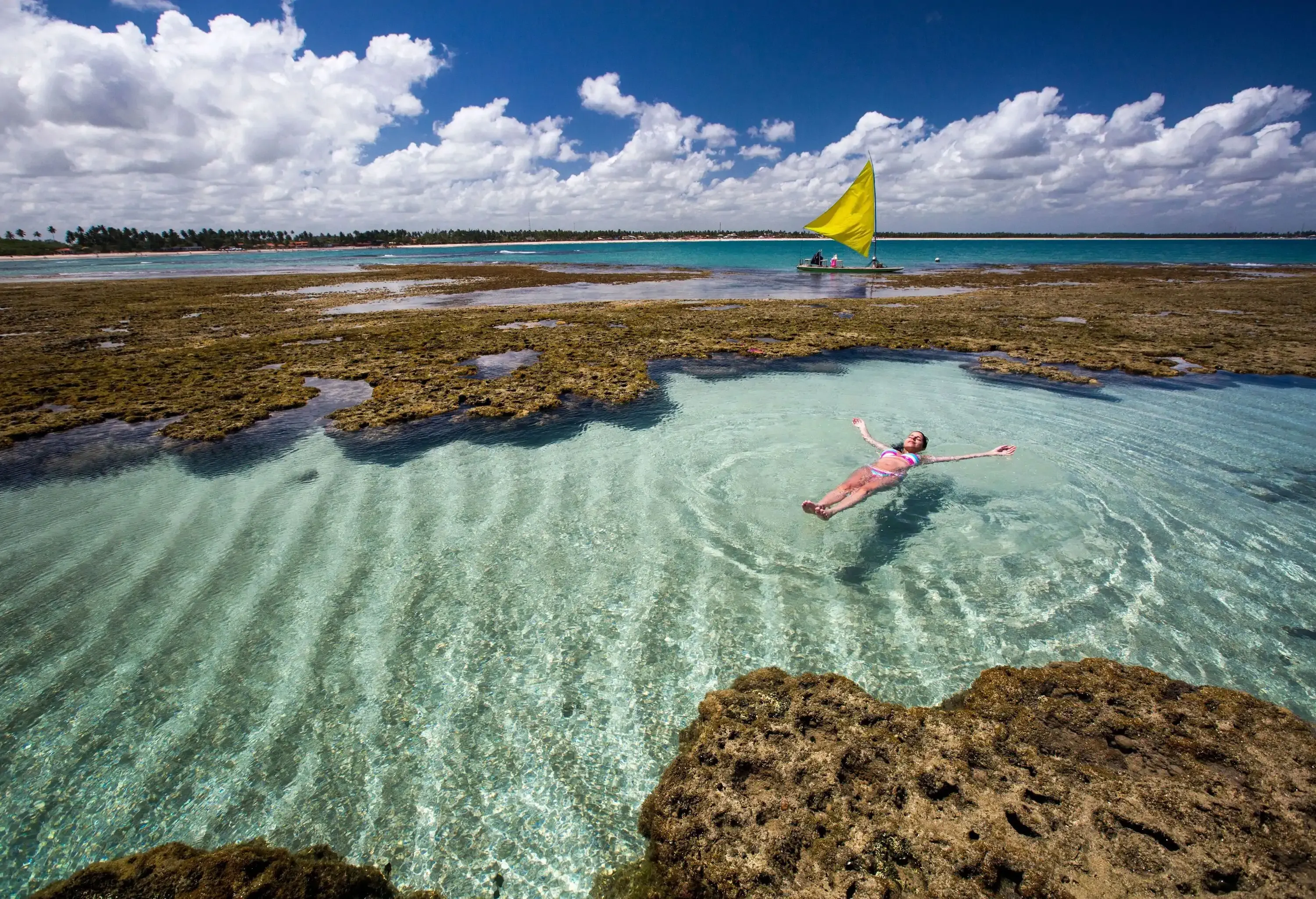 A woman floating in the clear ocean surrounded by coral reefs.