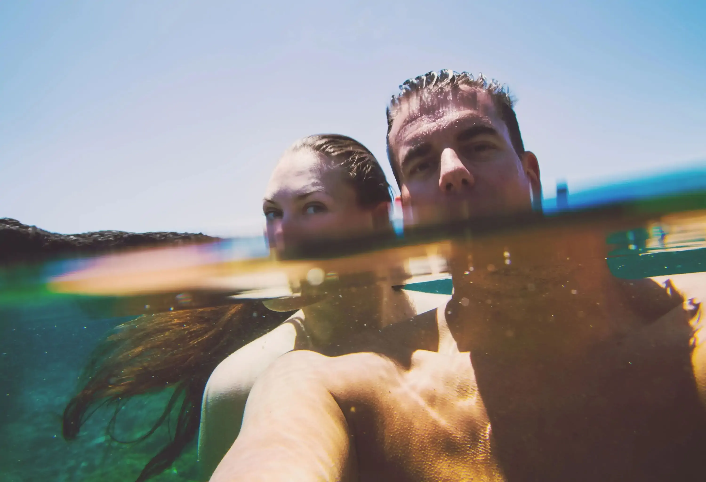 A lovely couple with their half faces submerged in the crystal clear seawater.
