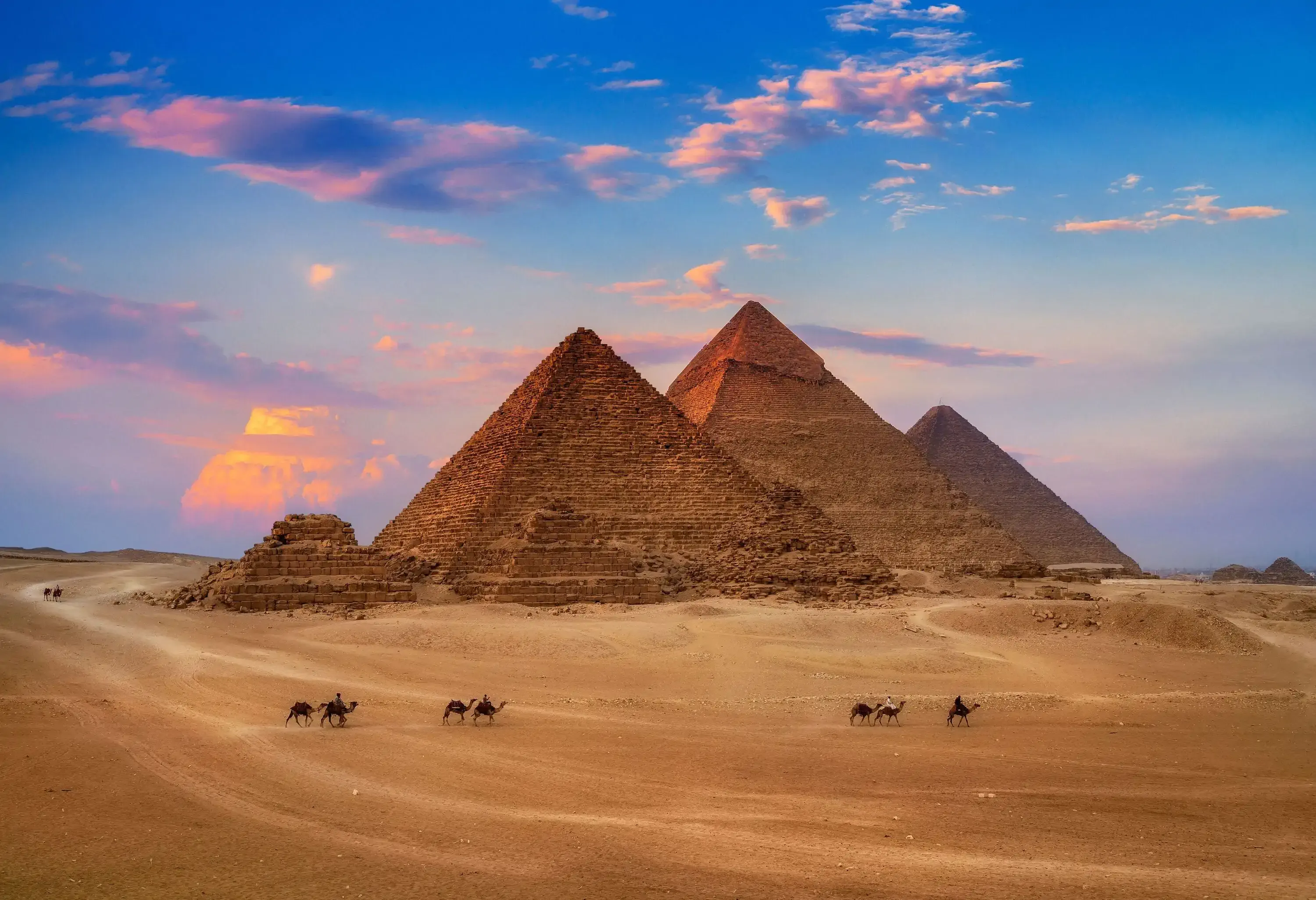 The Great Pyramid of Giza with camels following the trail marks around the base.