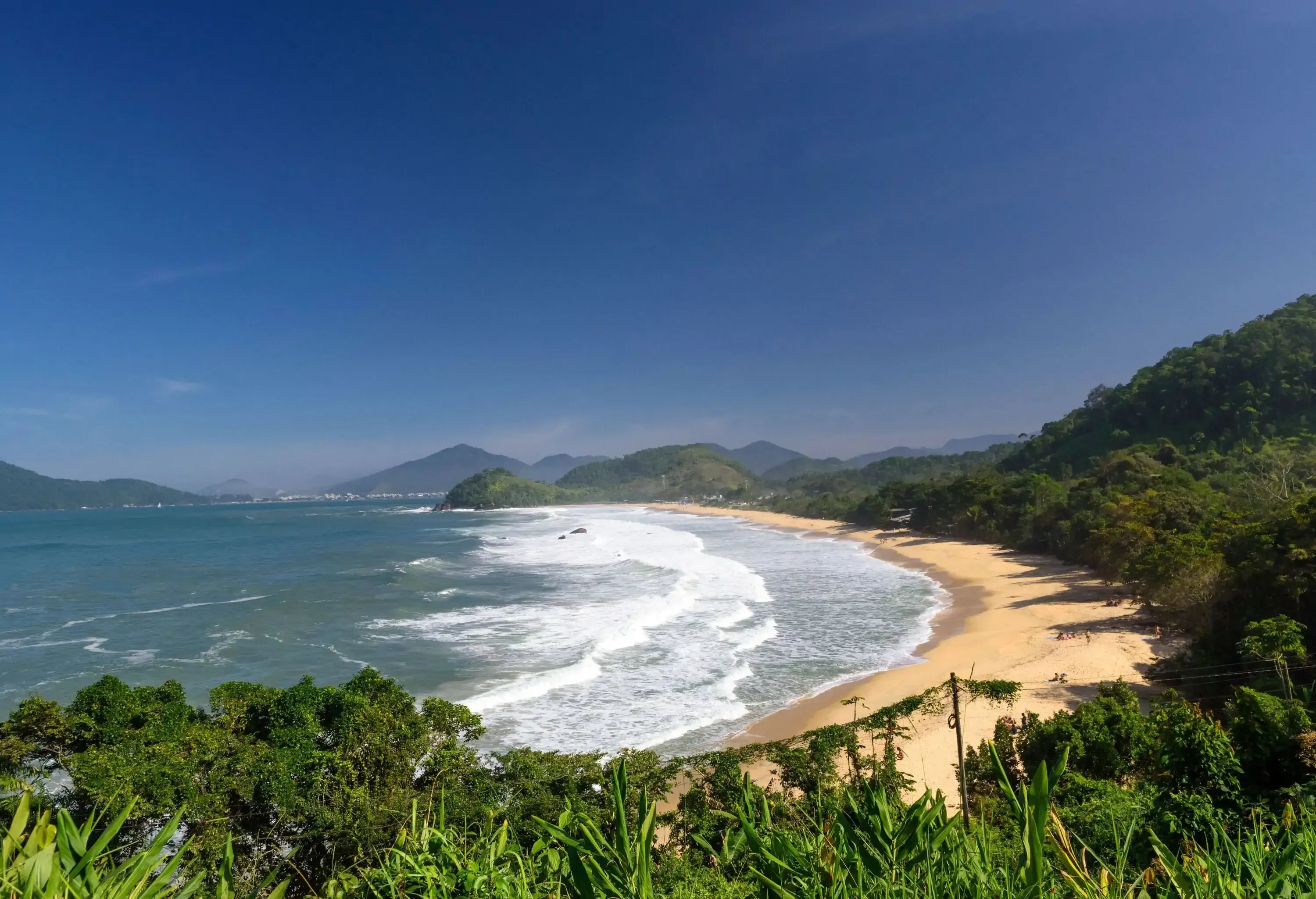 High hangle view of a bay with a wide sandy beach with surf