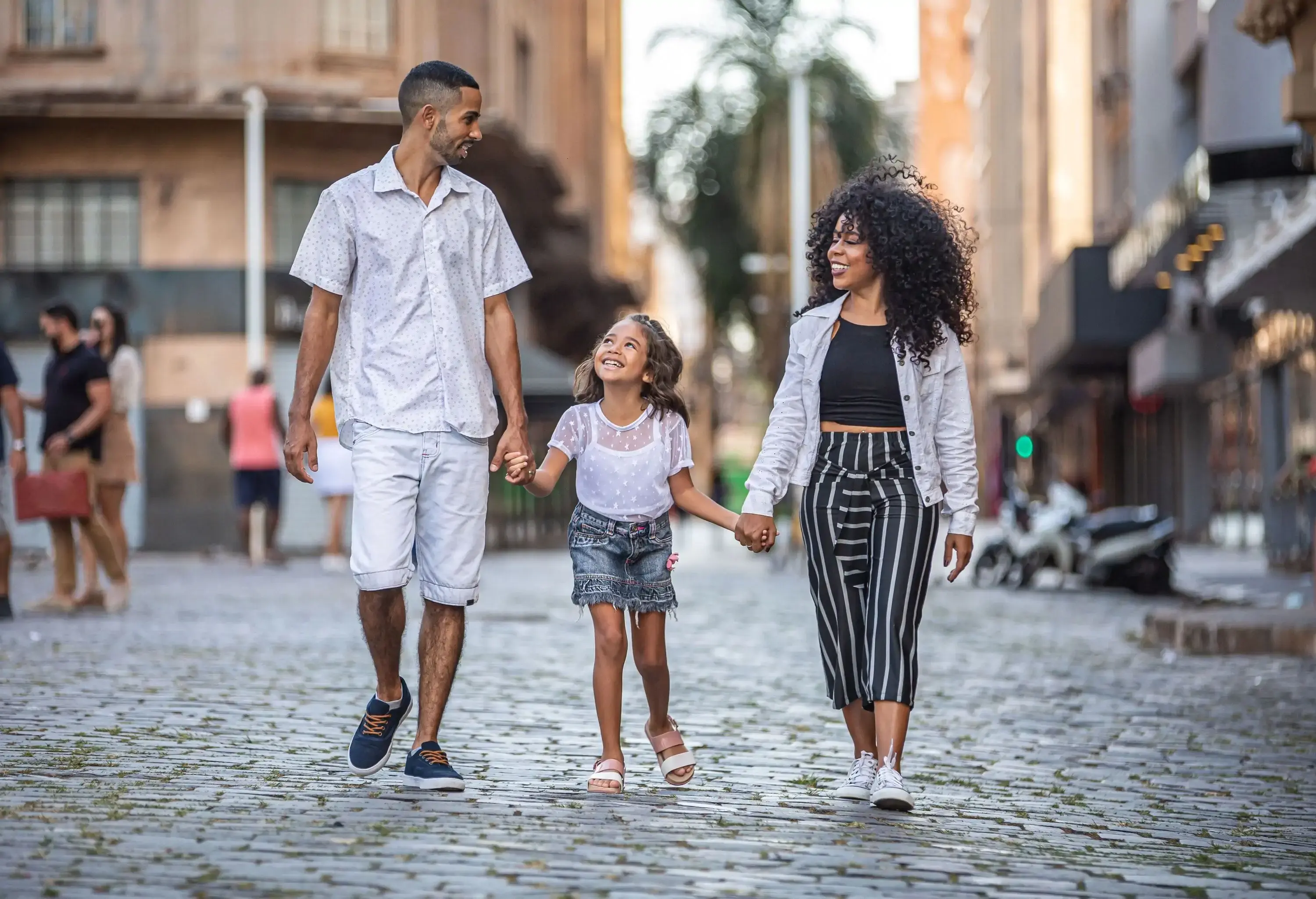 A couple with their kid between them walking through the city.