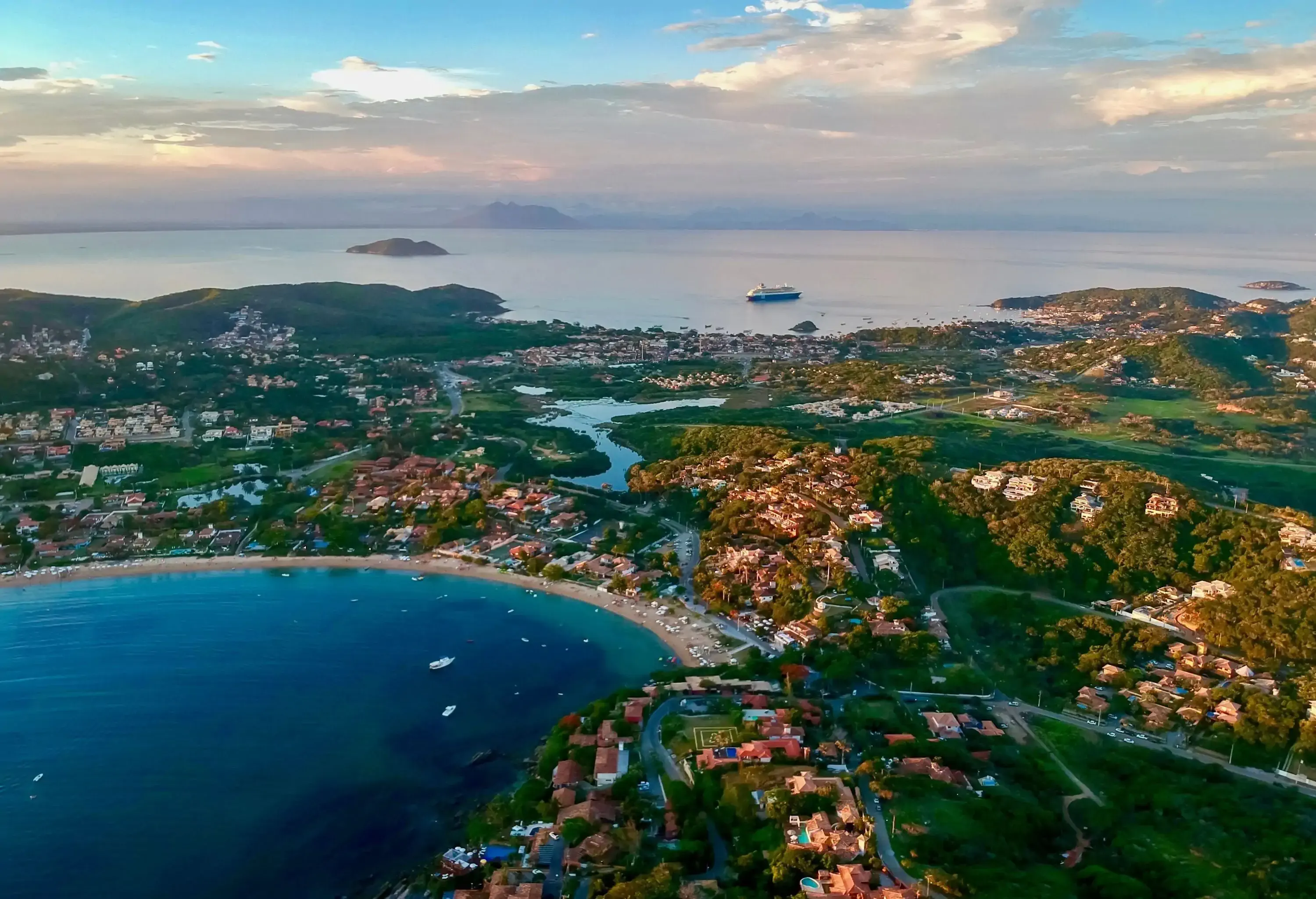 A breathtaking bay area embraced by verdant trees, with a quaint town nestled alongside.