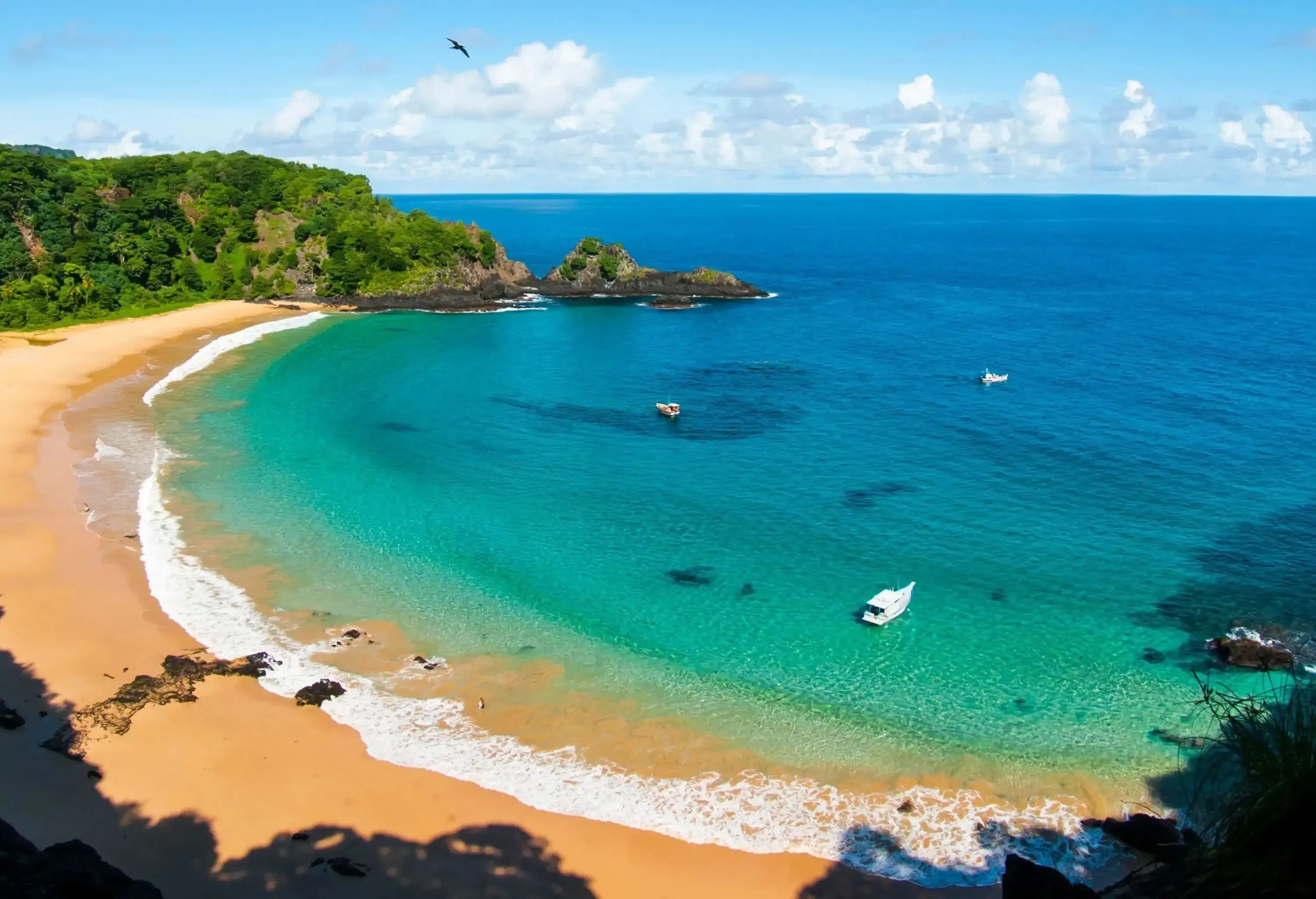 A pristine cove with a boat floating in turquoise waters.