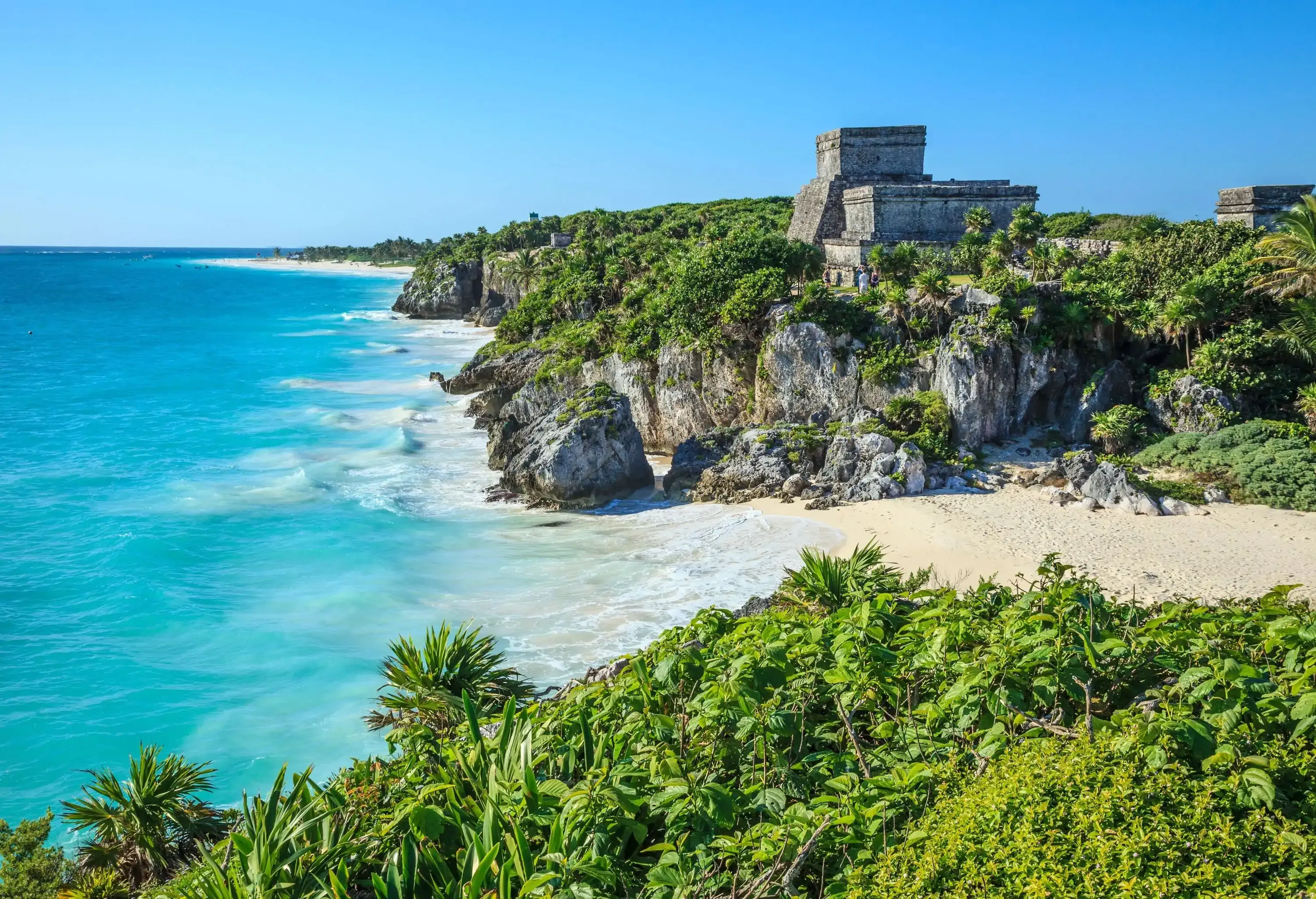 The Tulum Mayan ruins perched on a forested clifftop overlooking the turquoise ocean.