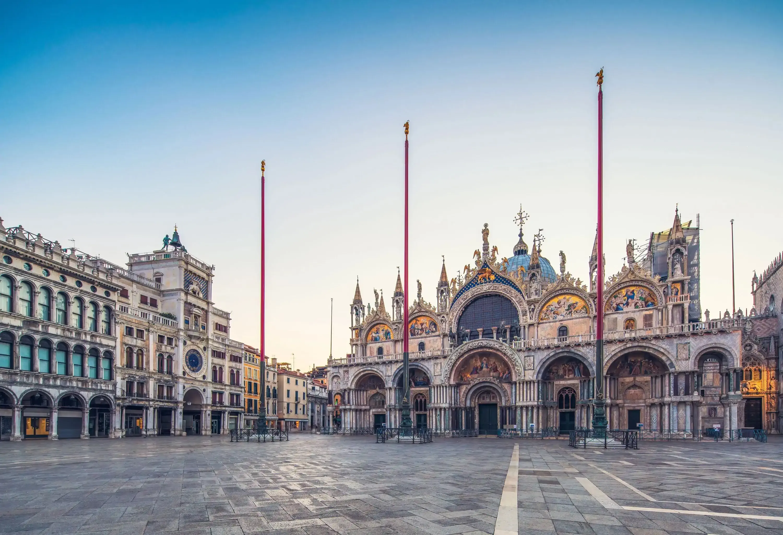 A cobblestone square surrounded by classical buildings with arched doors and windows and a cathedral with its iconic and stunning architecture.