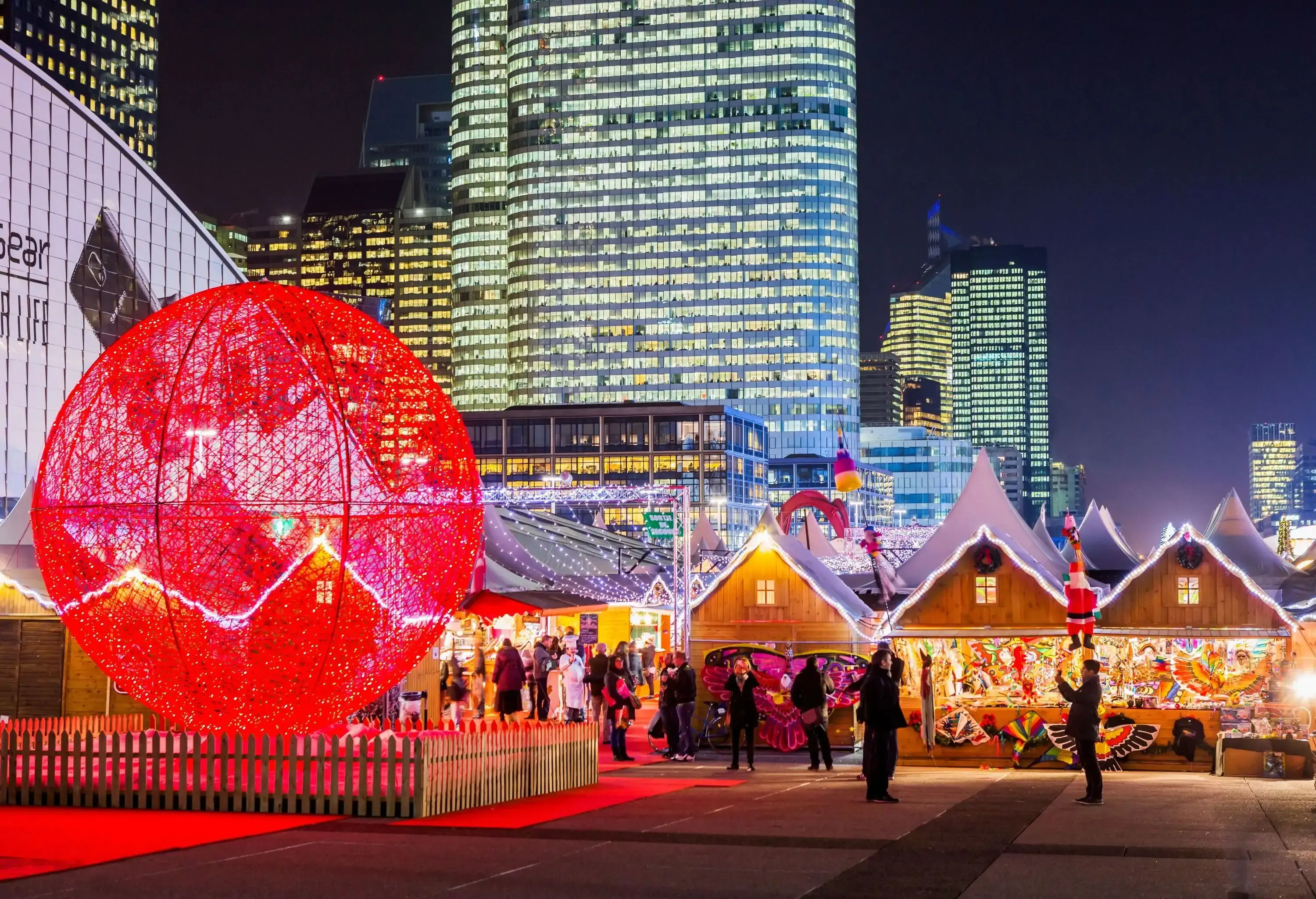 Christmas market lit up at night by skyscrapers