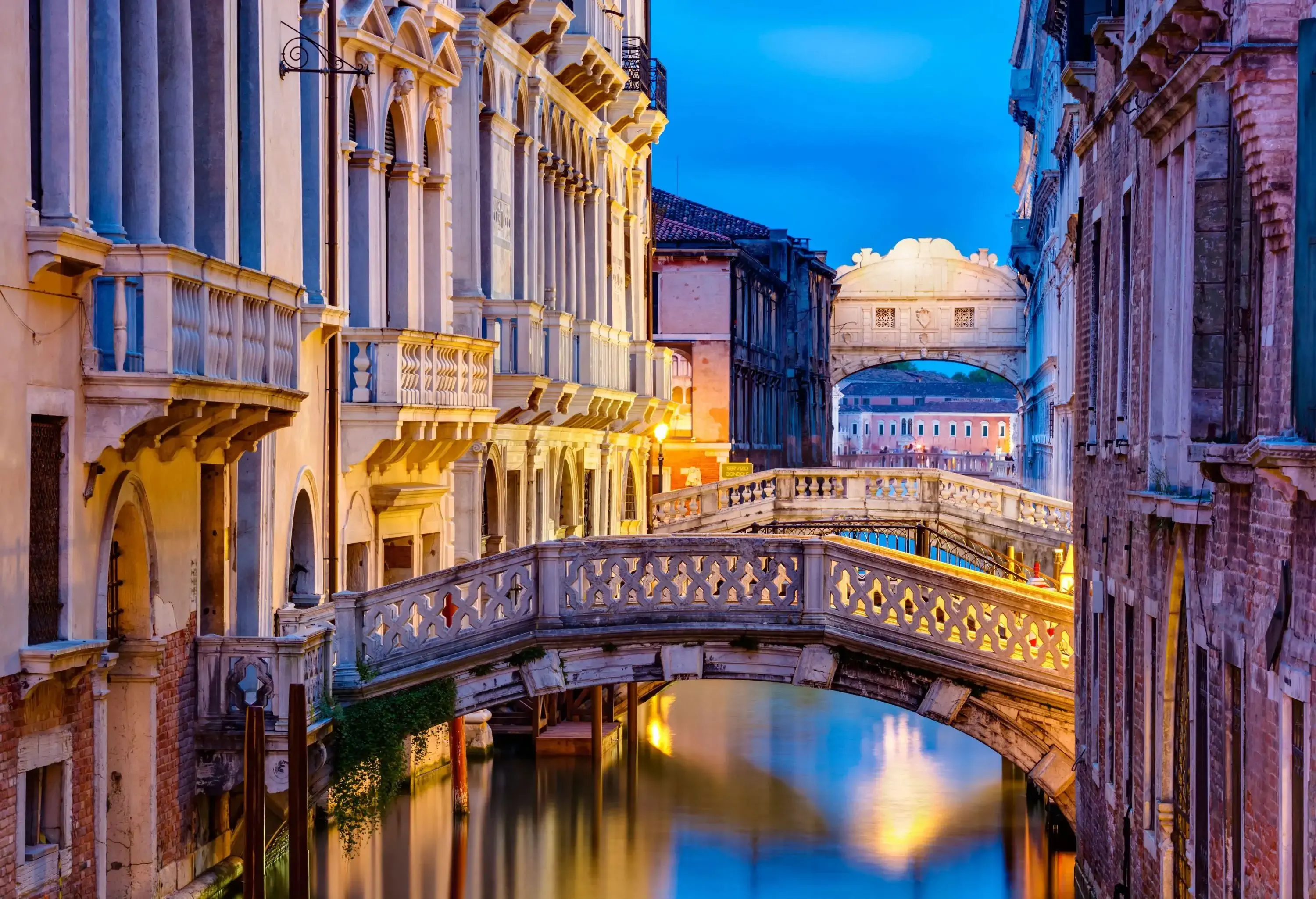 Short bridges across a canal between historic stone buildings.
