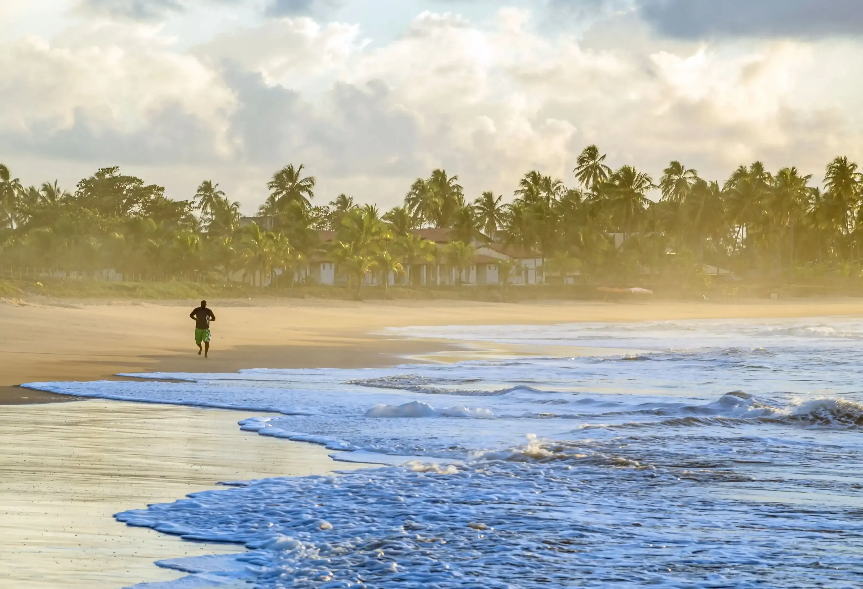 A man running along the beach as erratic swashes wash up across the sand.