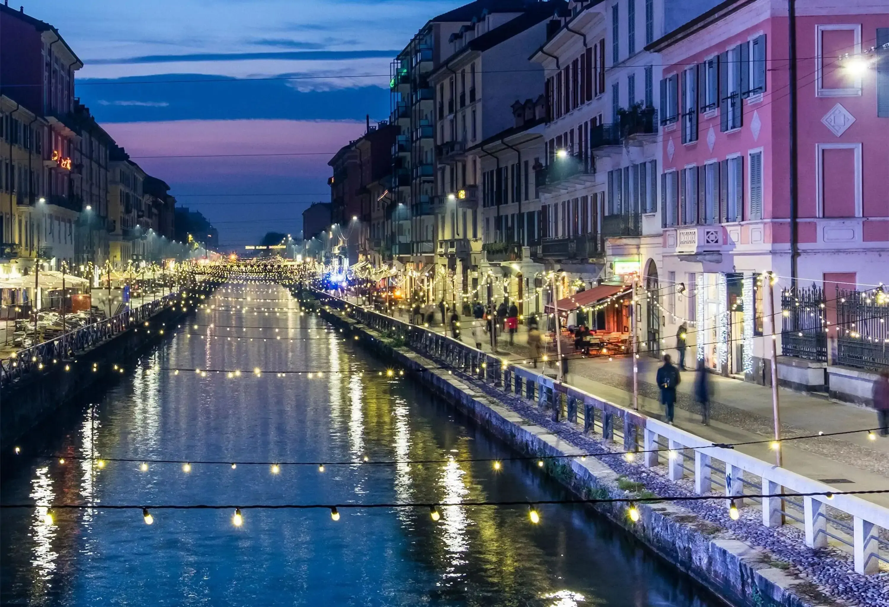 A canal system running through a neighbourhood with bright lights hanging across it.