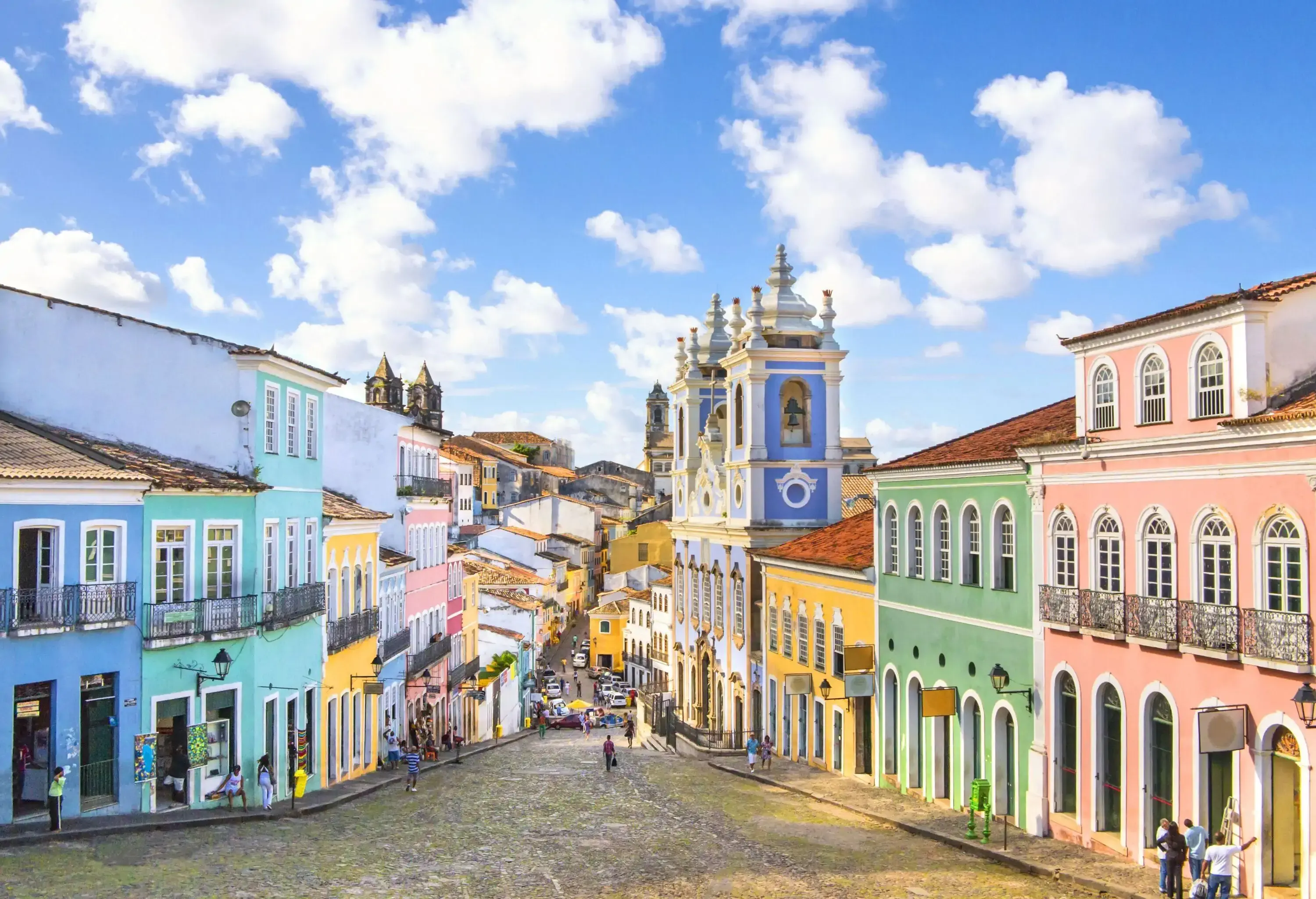 Colourful historic structures lining both sides of a sloping street.