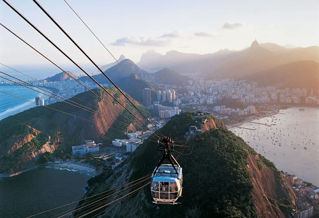 An aerial tram gracefully ascends, revealing the stunning mountainous landscape with a captivating coastal city sprawled below.