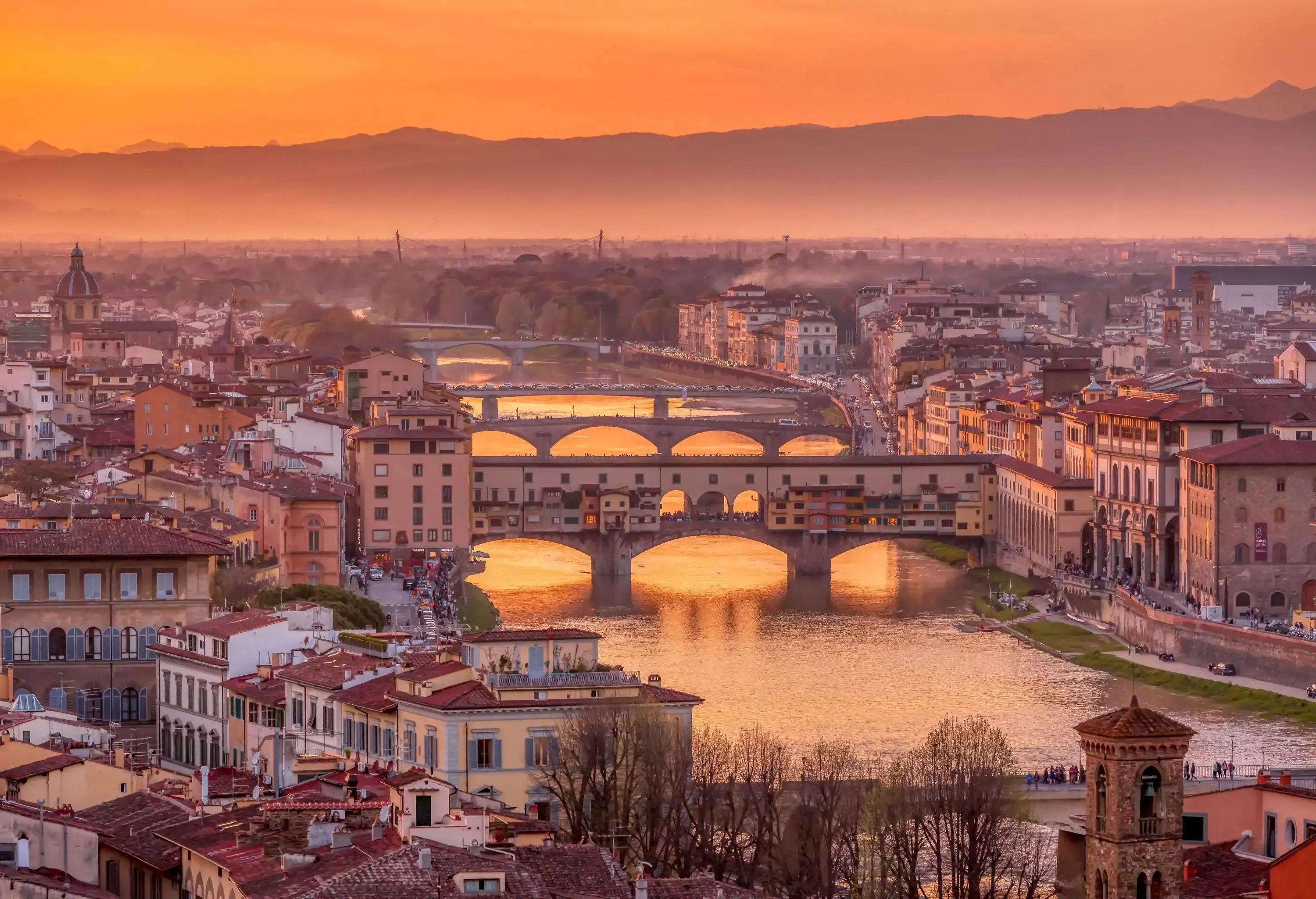 Several arch bridges connect thick clusters of compact buildings on both sides of the river.