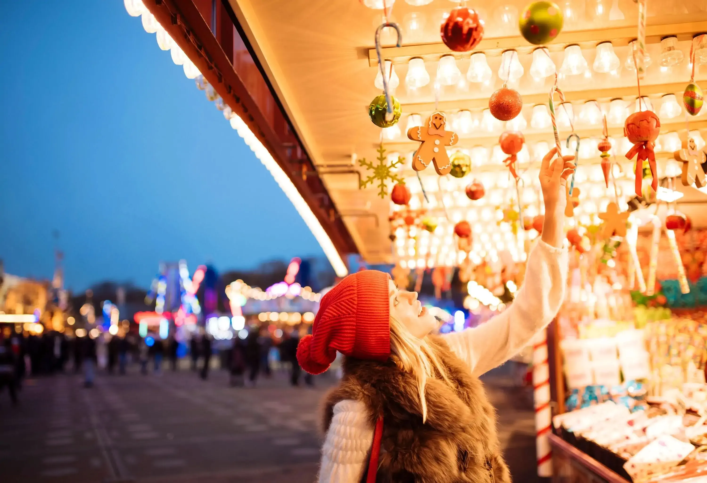 Woman wearing red beanie hat looking at Christmas decoration at winter market