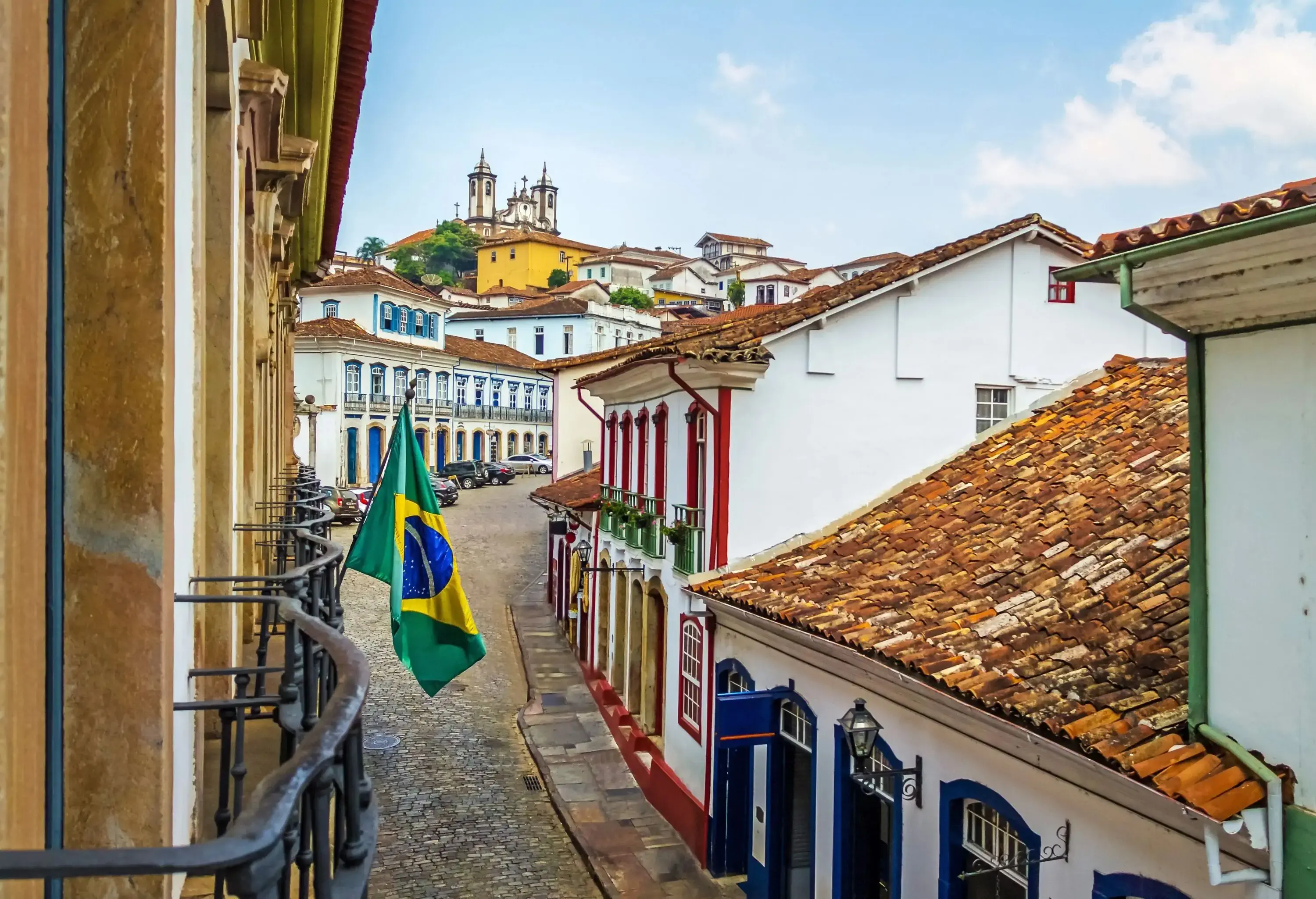 A cobbled narrow street between colourful and classic buildings with brick roofs.