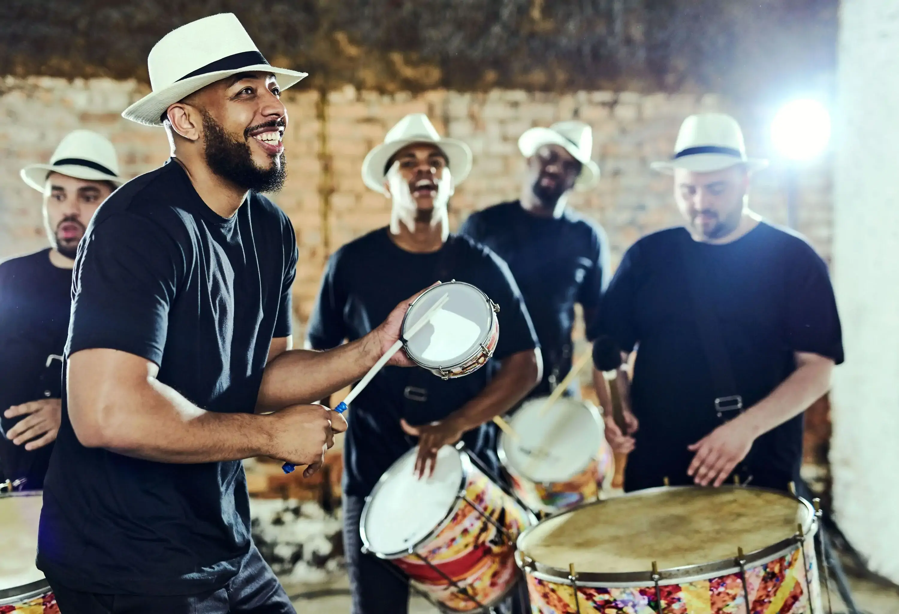 A male group band playing drums indoors during a music festival.