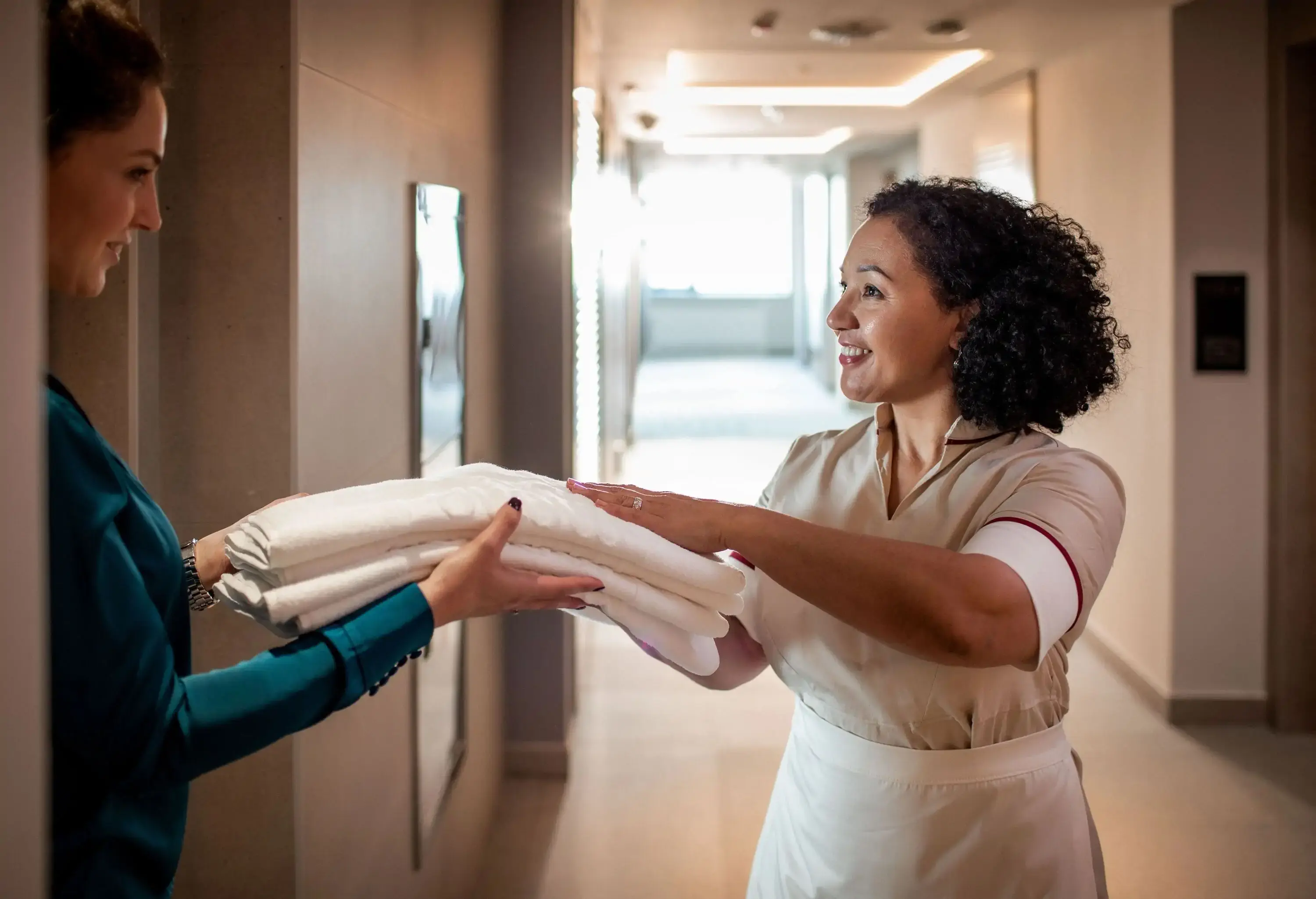 Close up of a maid changing the towels for a young lady staying at the hotel