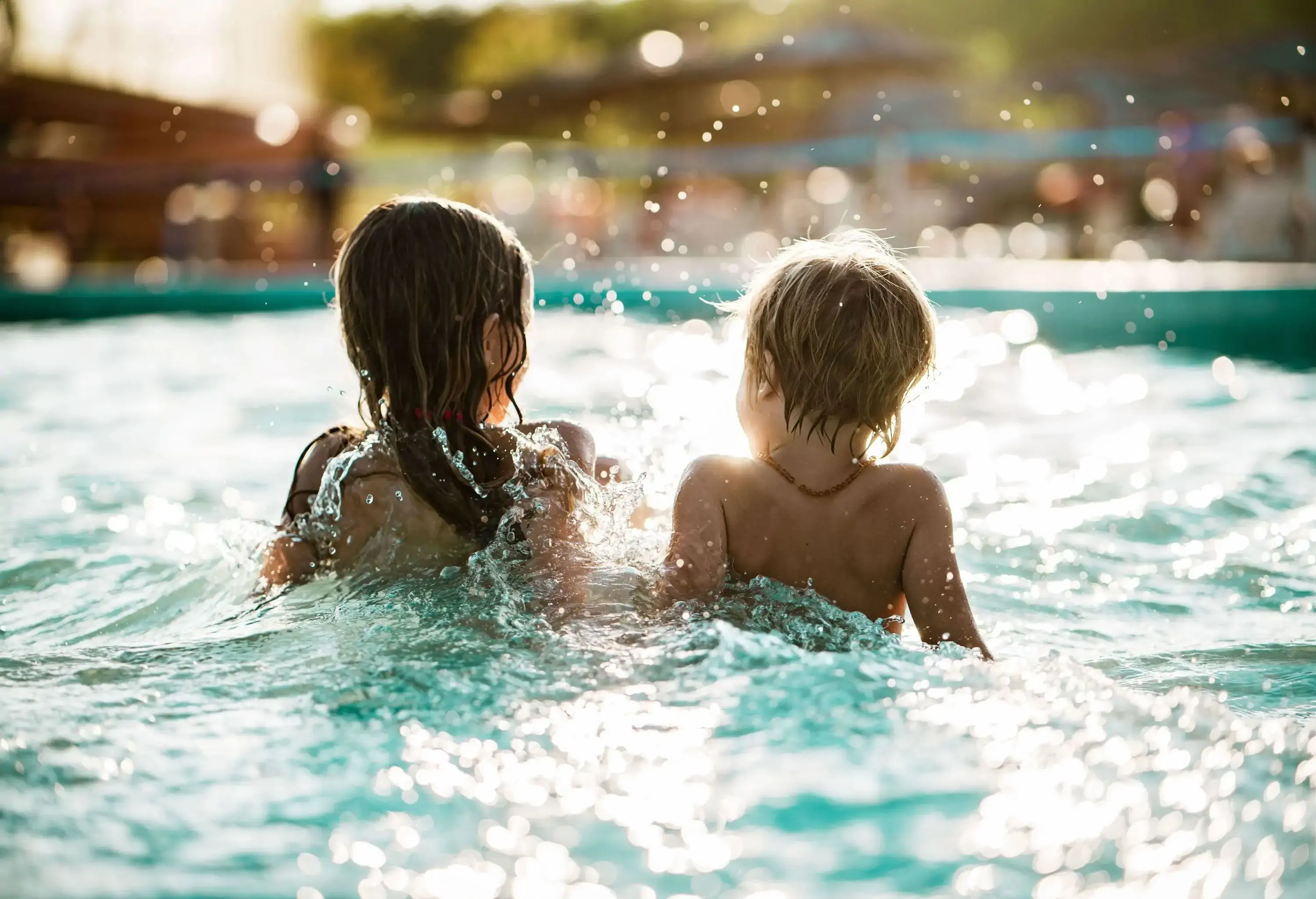 Two little children submerged and enjoying the splashes in a pool.